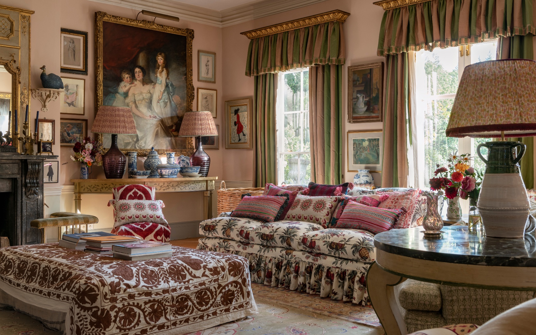 a traditional english drawing room with a white and red floral sofa and matching ottoman, pink and green striped curtains and a large portrait painting in a gold gilded frame