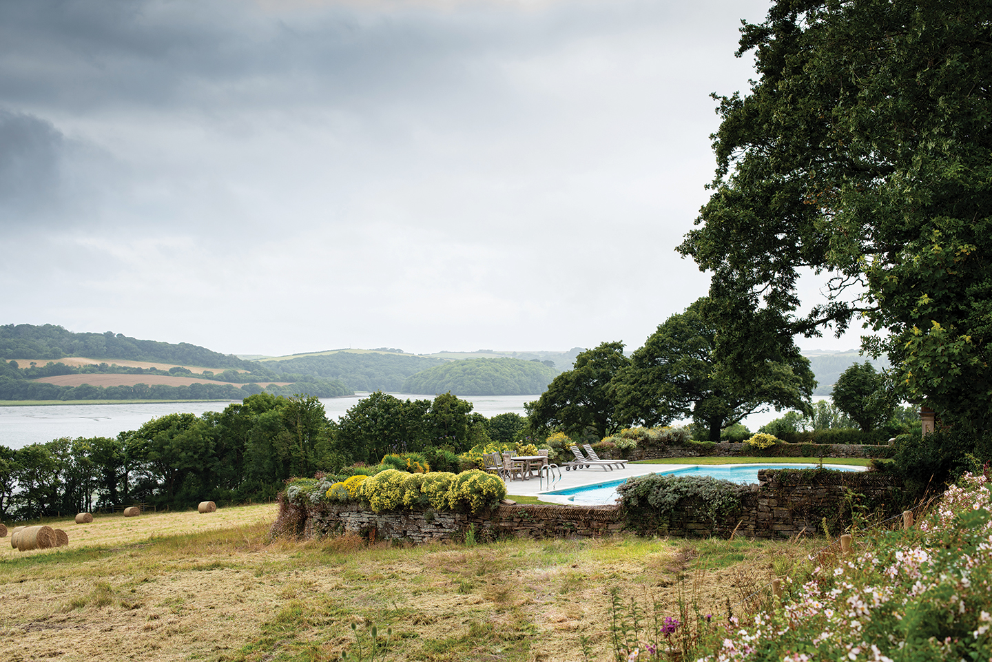 a swimming pool set in rustic country gardens with the Lynher River in the background