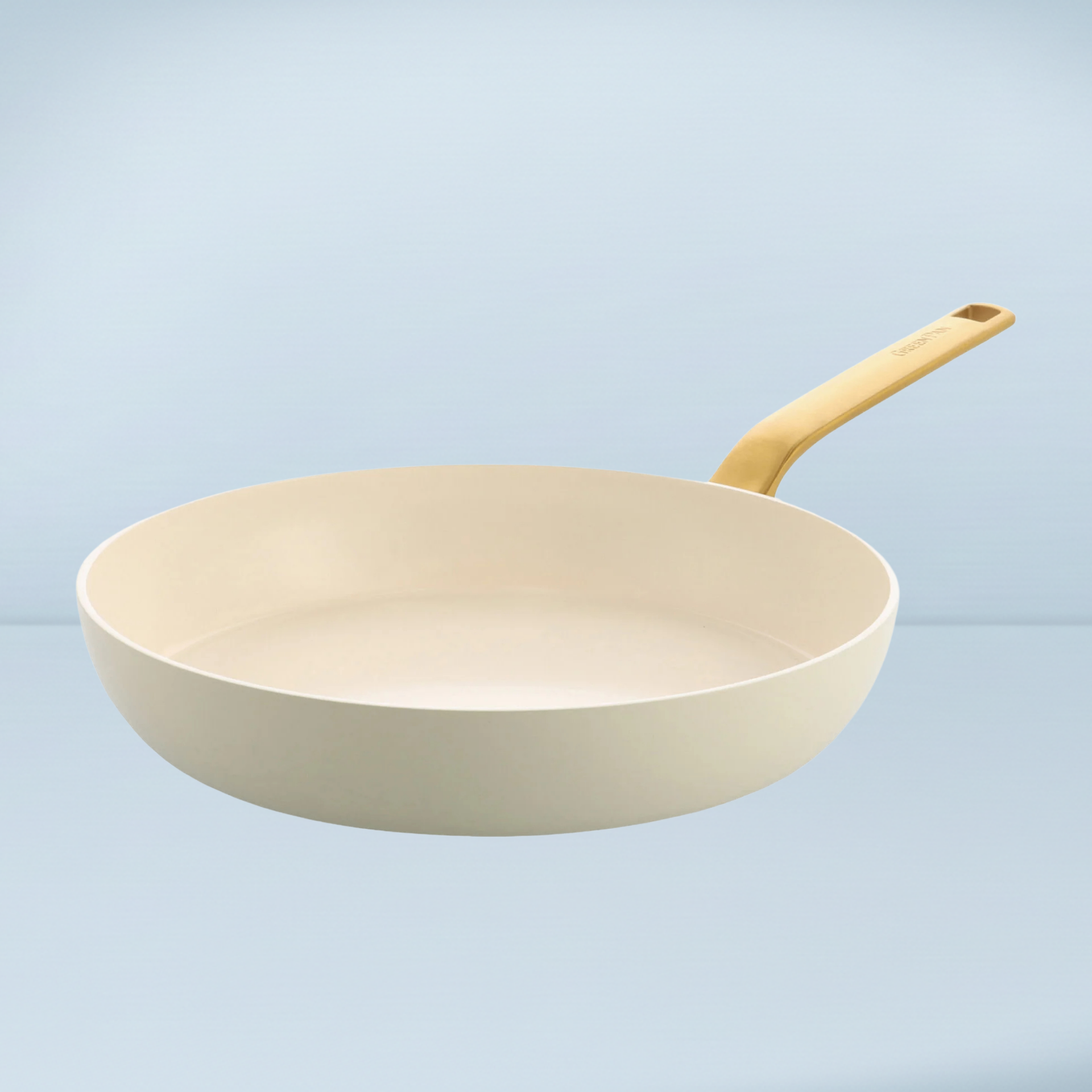 a cream ceramic frying pan with a gold handle