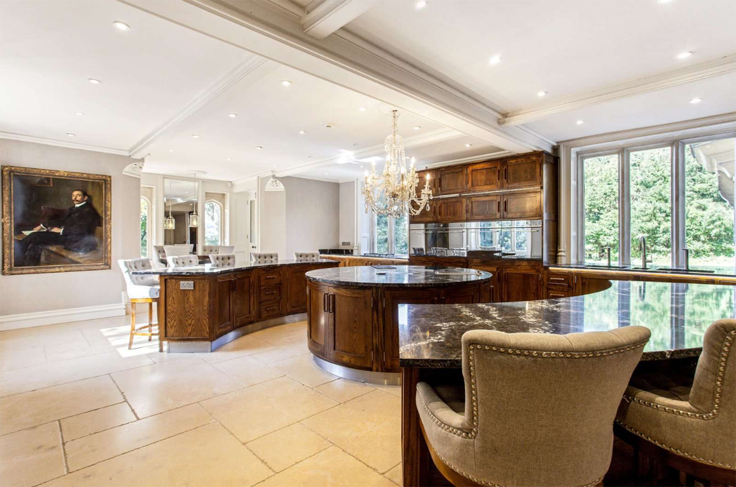 a kitchen with dark brown cabinetry, dark marble countertops and a large portrait painting in a gilded frame