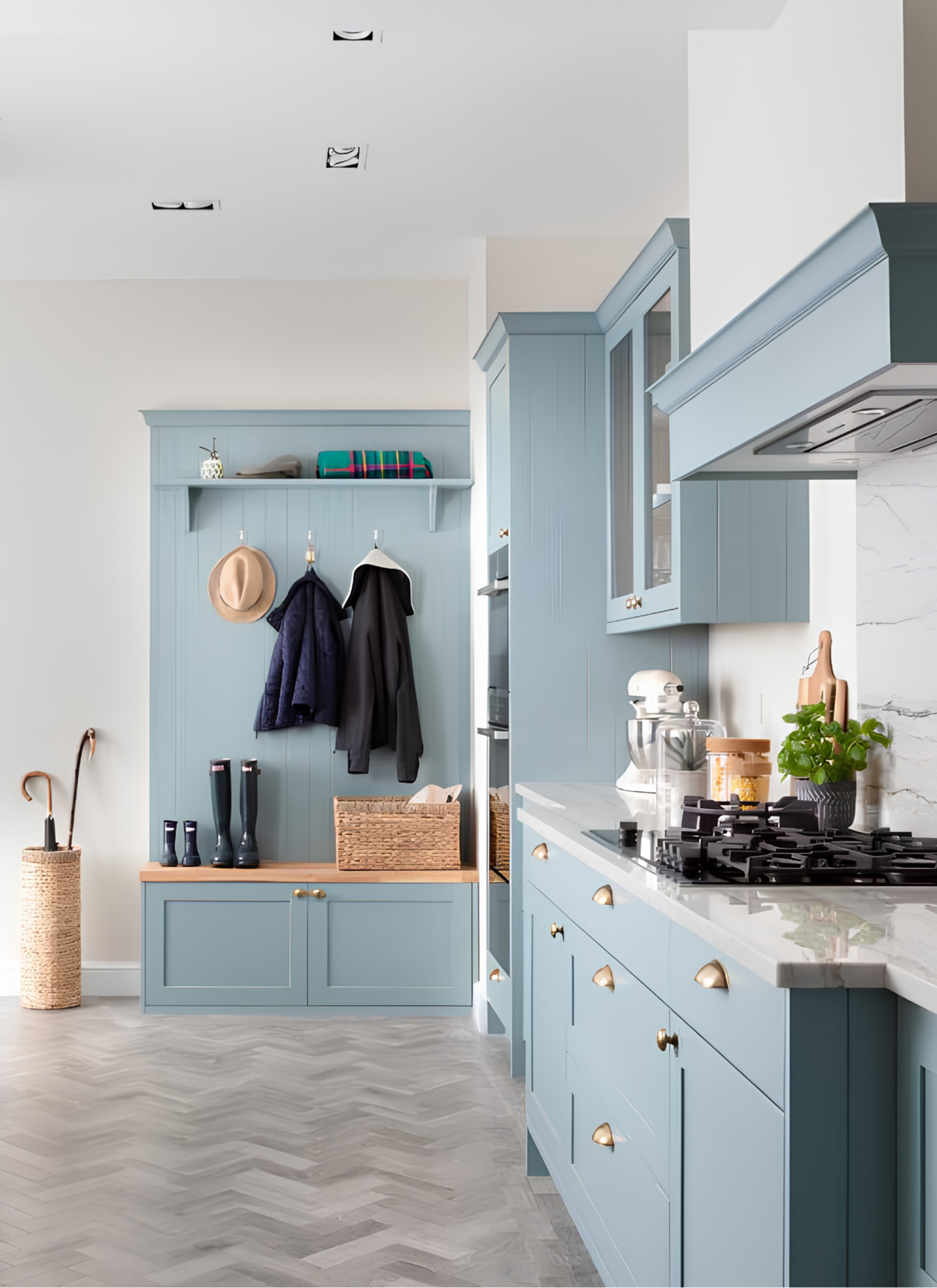 a kitchen and boot room area with pale blue cabinetry, grey parquet flooring and white marble countertops