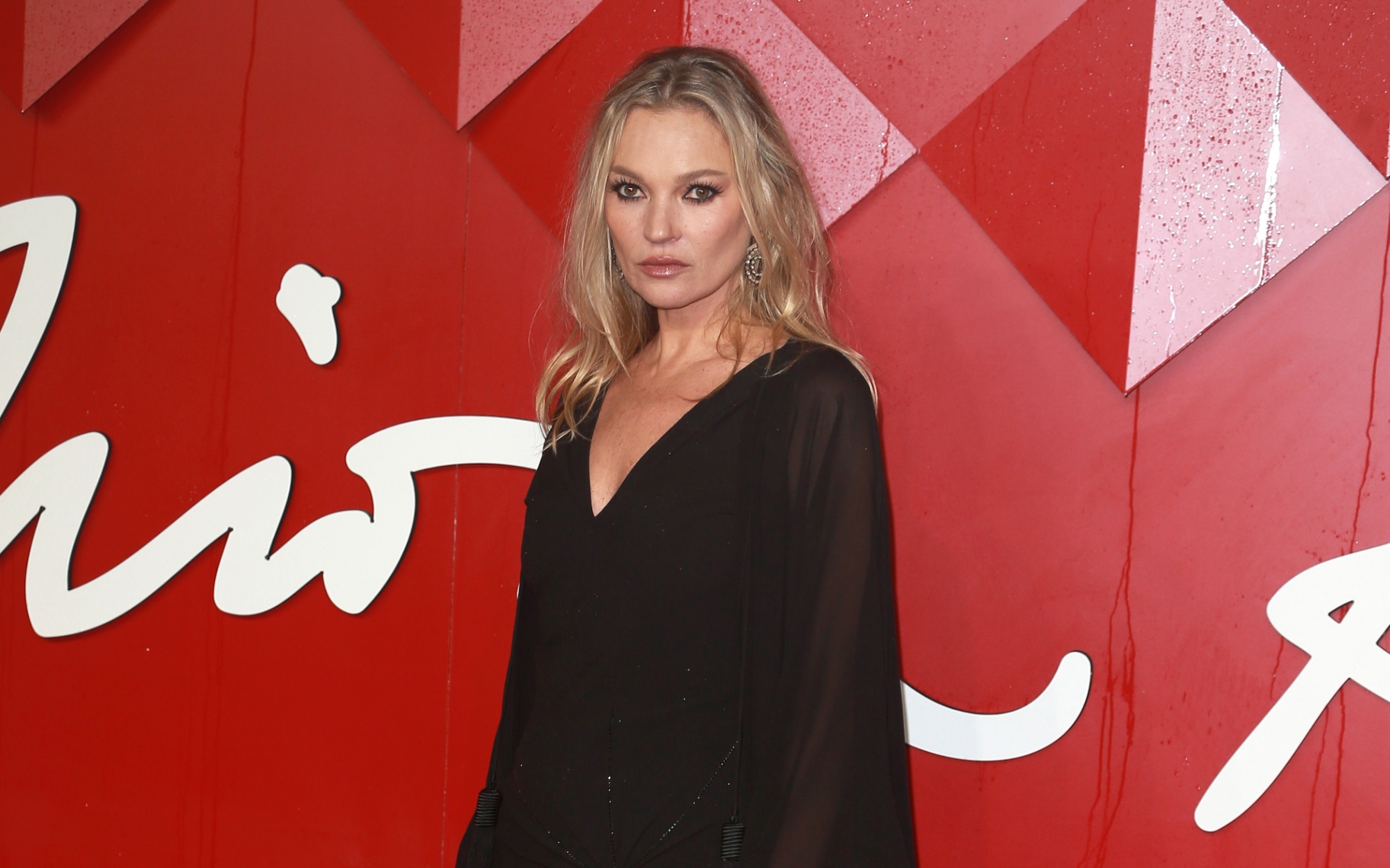kate moss in a black dress agaisnt a red background