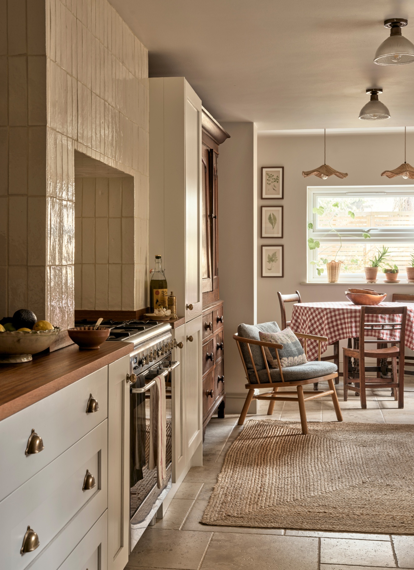 a kitchen with pale cabinets, a jute rug and a round dining table with ared and white gingham cloth