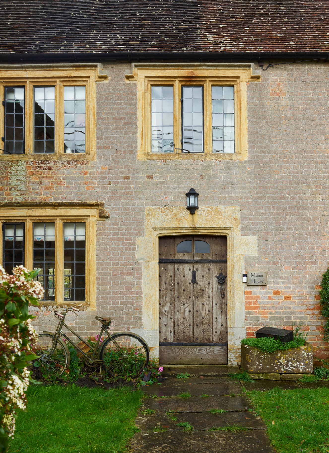 the front of an house with an old wooden door and a bicycle next to it