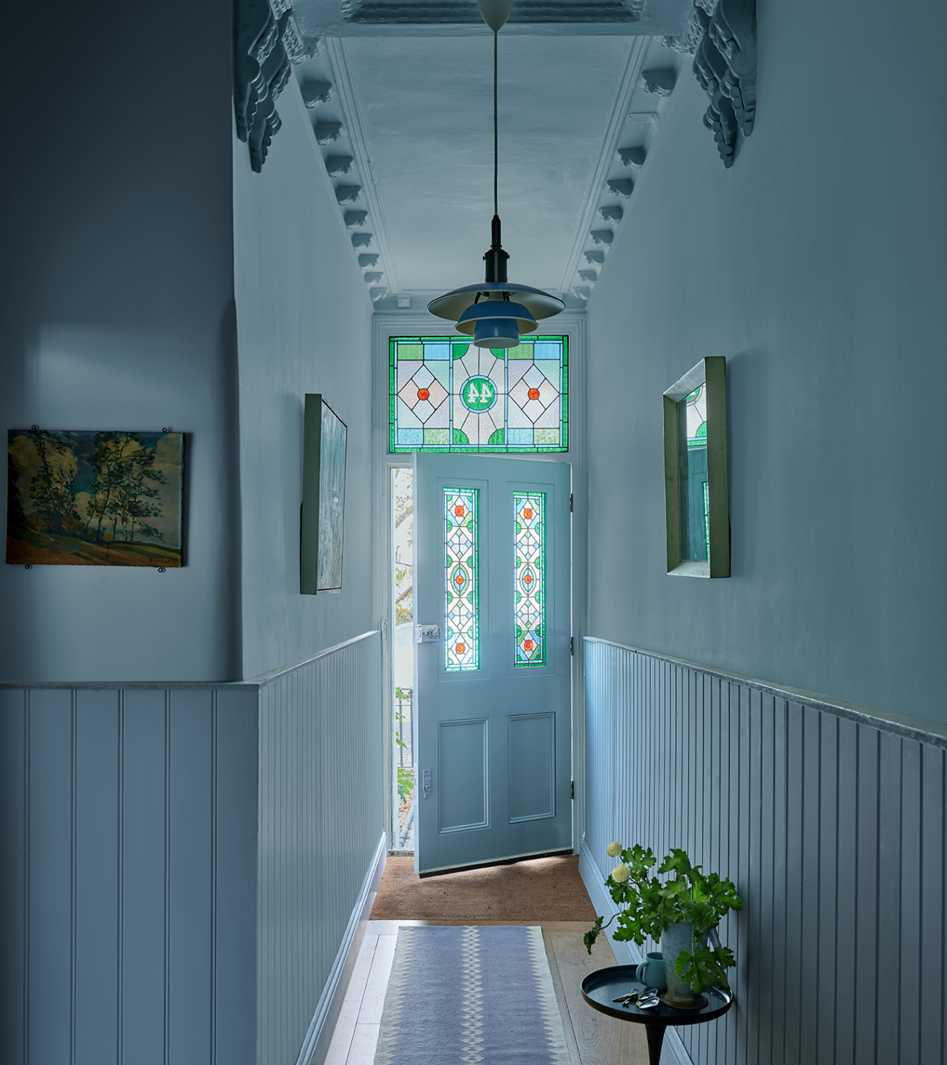 a colour drenched pale blue hallway with blue walls and ceiling and an open stain glass door