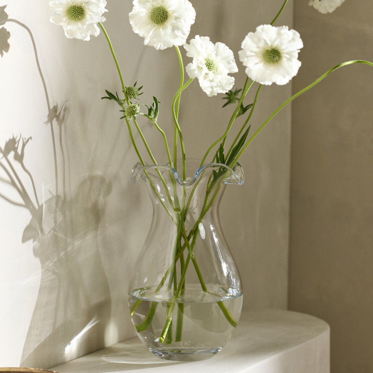 a glass vase with a ruffle rim and white flowers