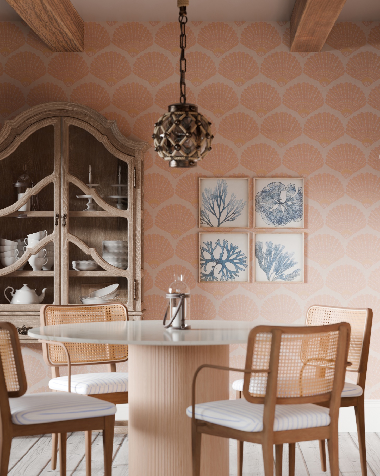 a dining room with a coral pink wall with large seashells print, a round dining table with rattan dining chairs and a large wooden dresser filled with china