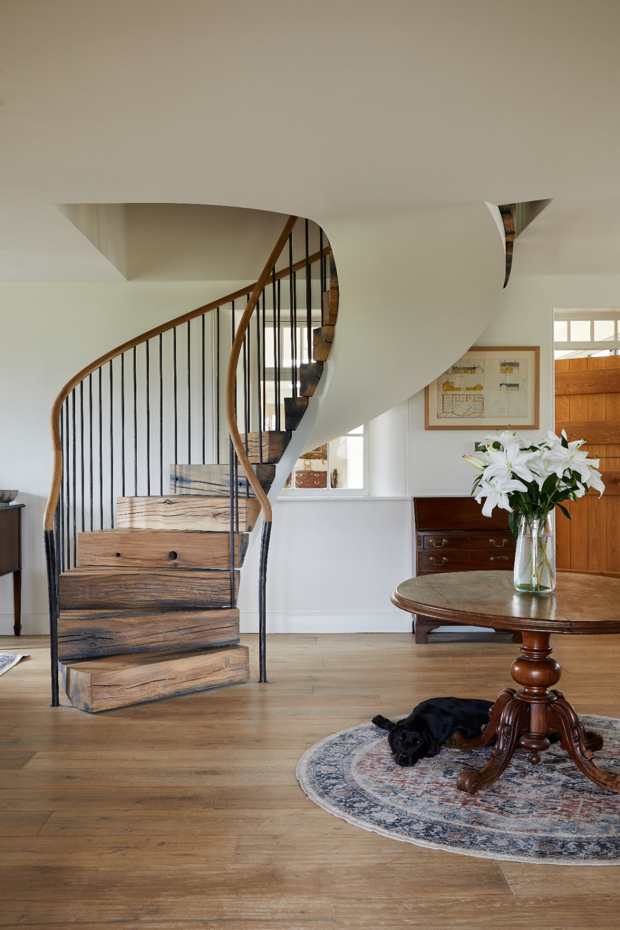 Bespoke helical staircase is made from old oak lock gates, each tread hand carved, and finished with round oak handrails
