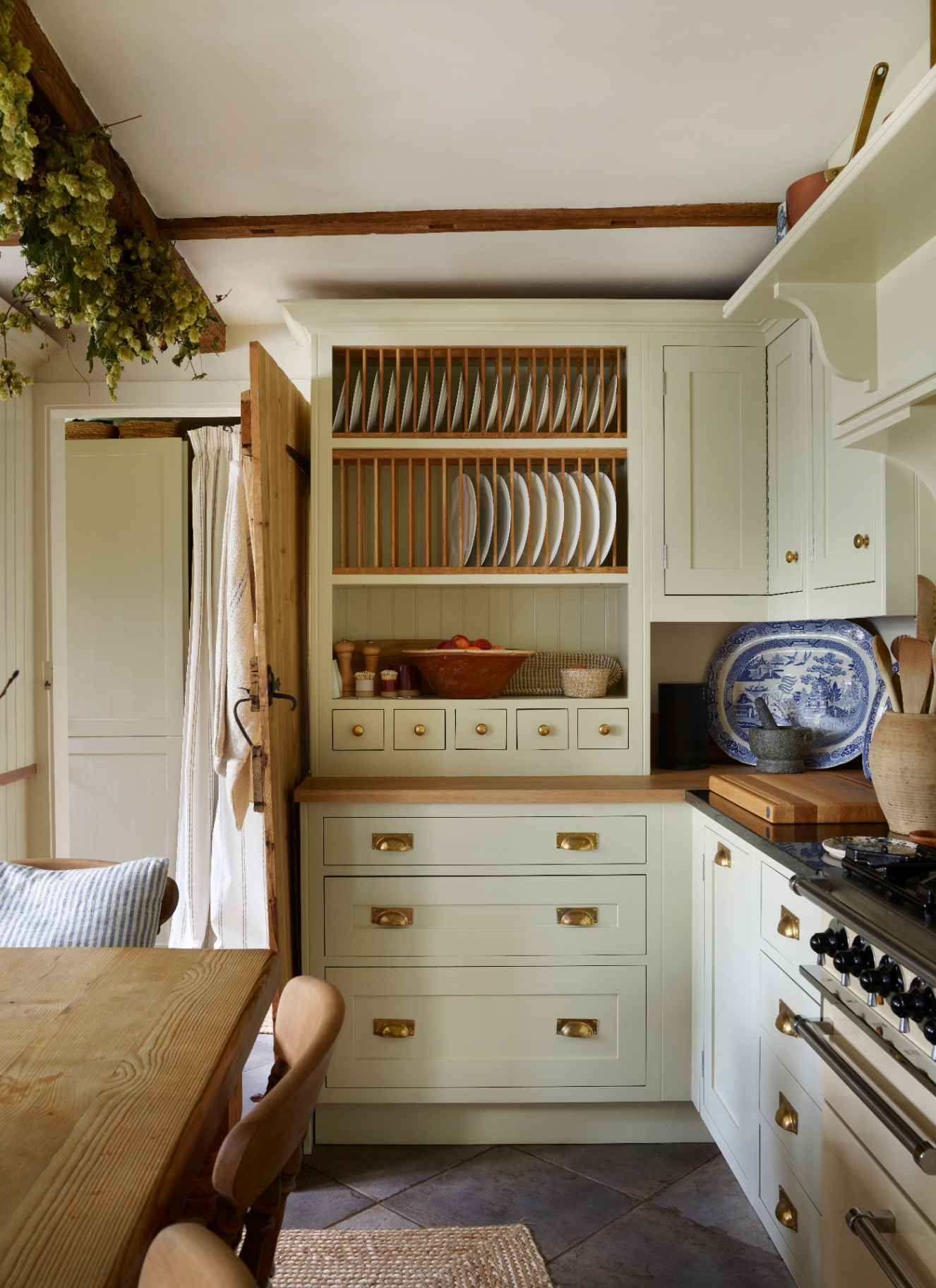 a cottage kitchen with sage green cabinetry and a plate dresser on top of the countertop filled with plates