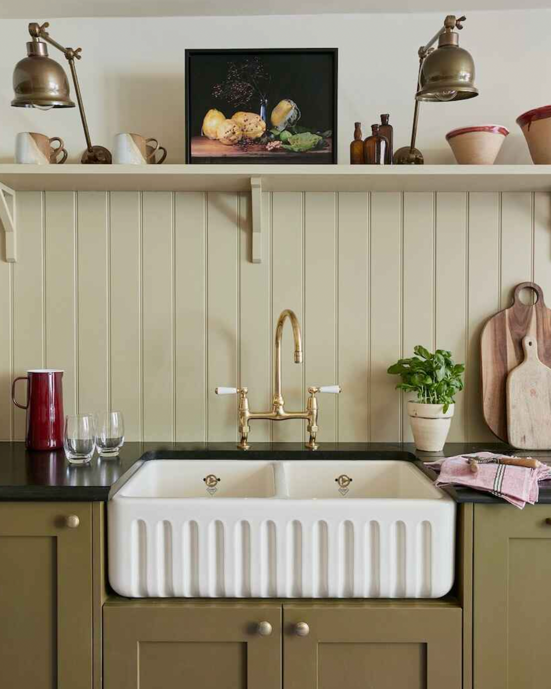 laura stphens kitchen with cream wooden tile splashback, an open shelf, belfast sink and olive green cabinetry