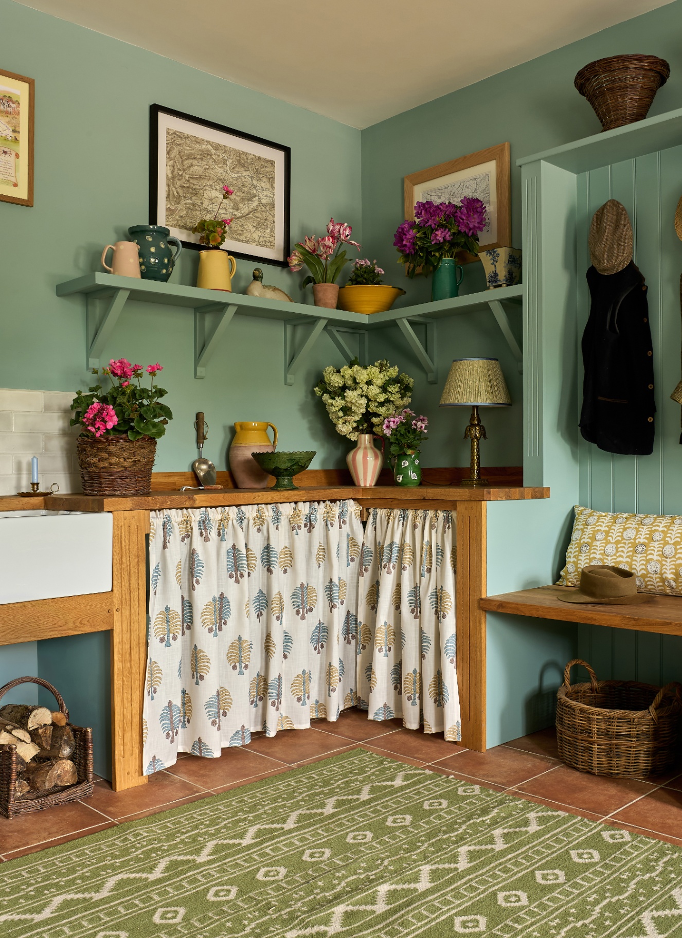 a boot room and utility room with pale blue walls, wooden work tops, a whiet, blue and yellow patterned sink skirt and a green and white patterned rug