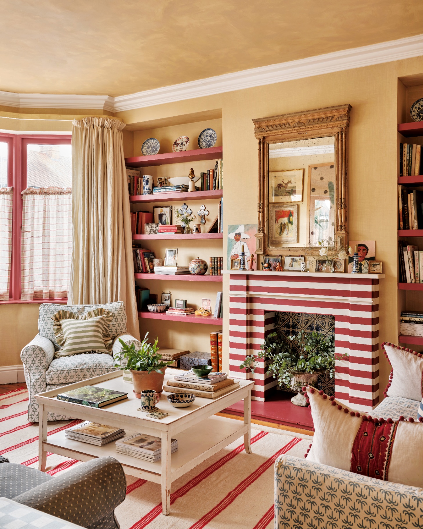 a living room with a red and white stripe painted fireplace, a white and red stripe rug under a small white square coffee table and red painted alcove shelving