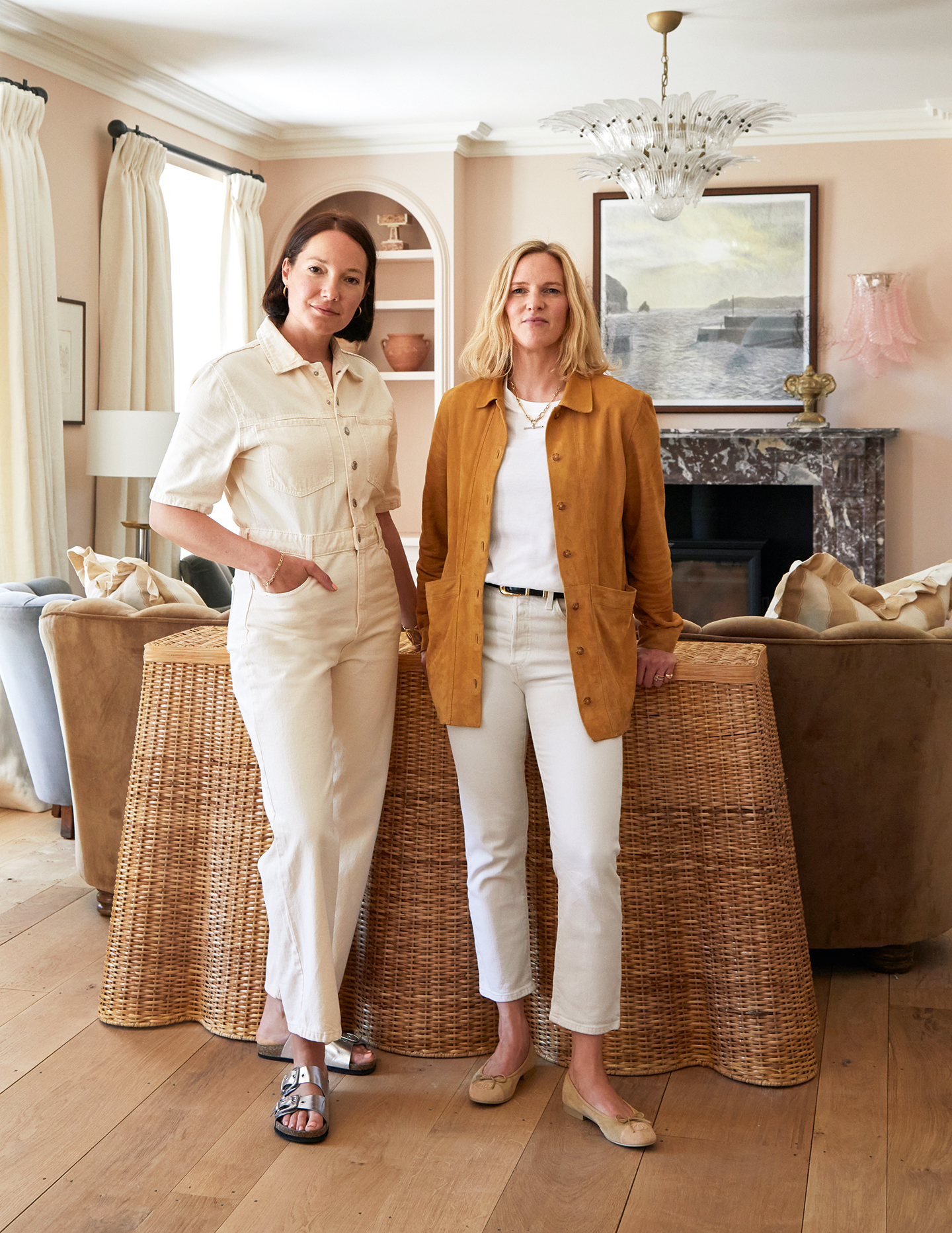 Two women stand in front of a pink living room
