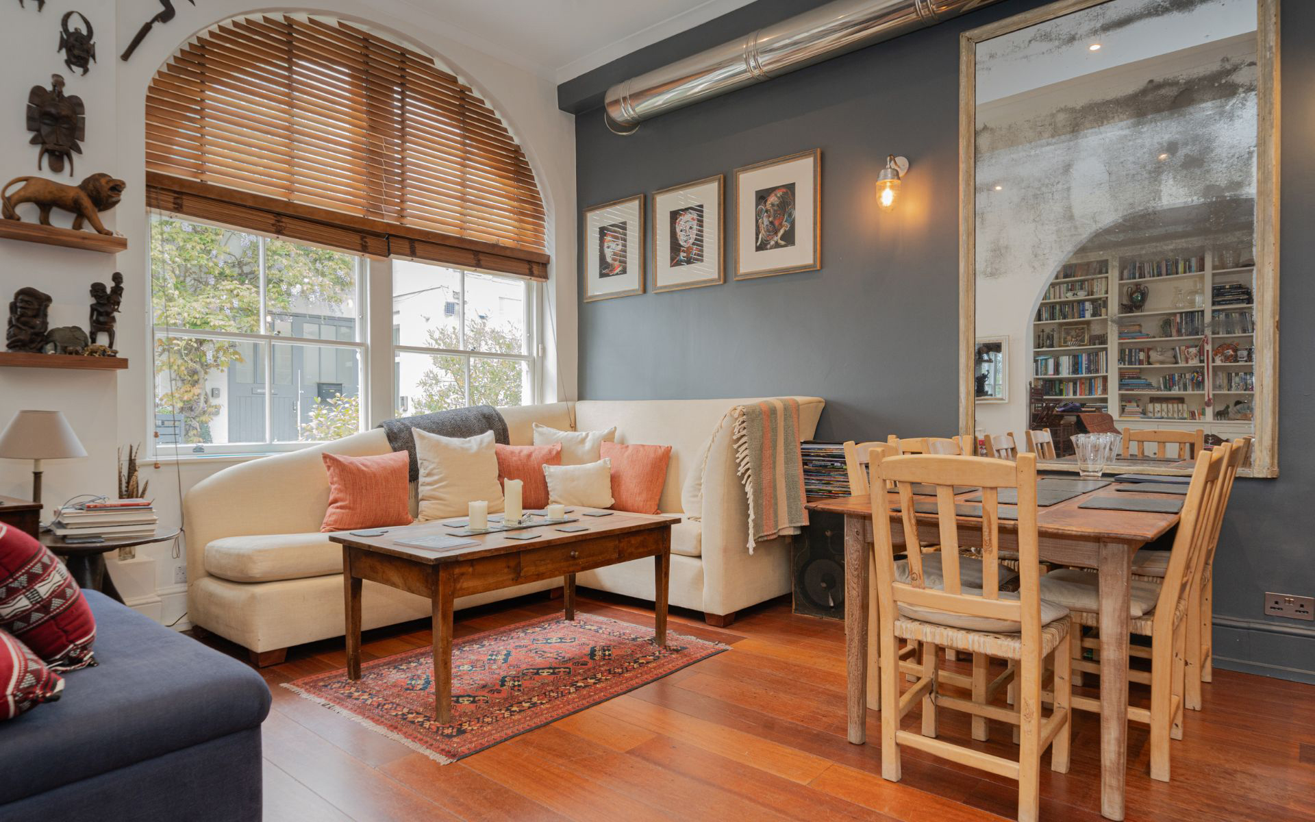 the living room of Madonna's former london home, with a large arched window, cream sofa and small wooden dining table and chairs