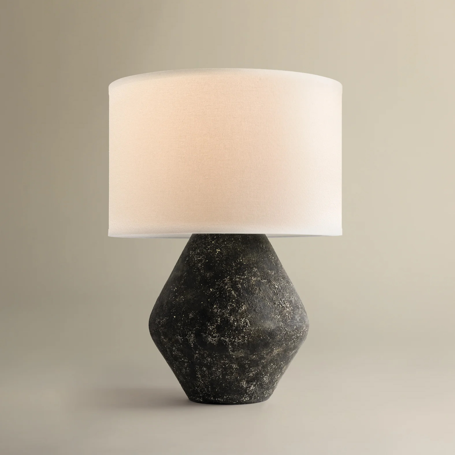 a black stone lamp base with a large cream shade on a grey background
