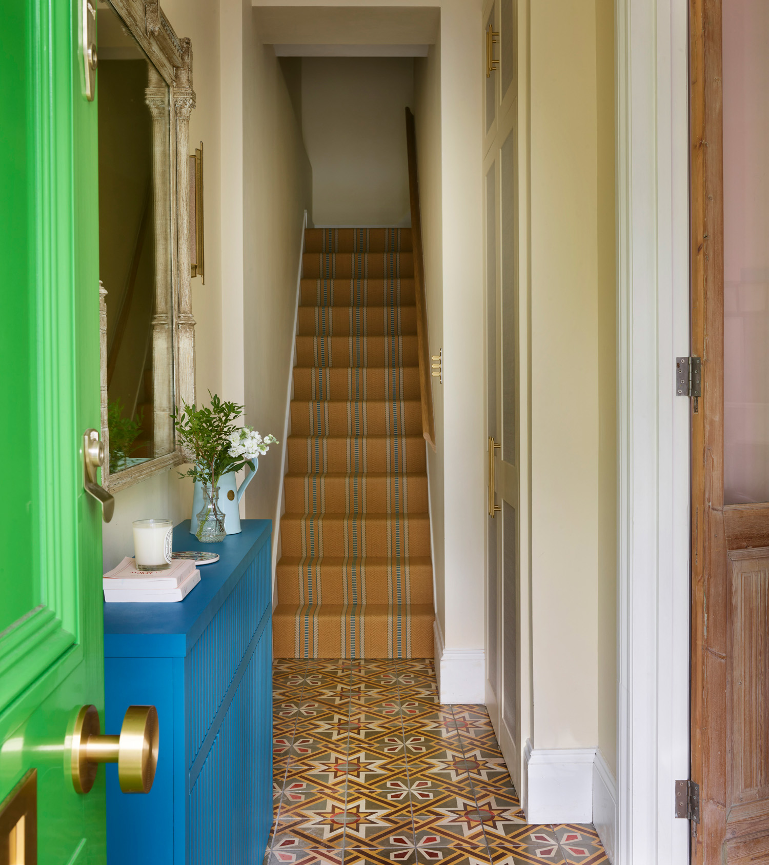 a narrow hallway with a blue console table and bright green front door