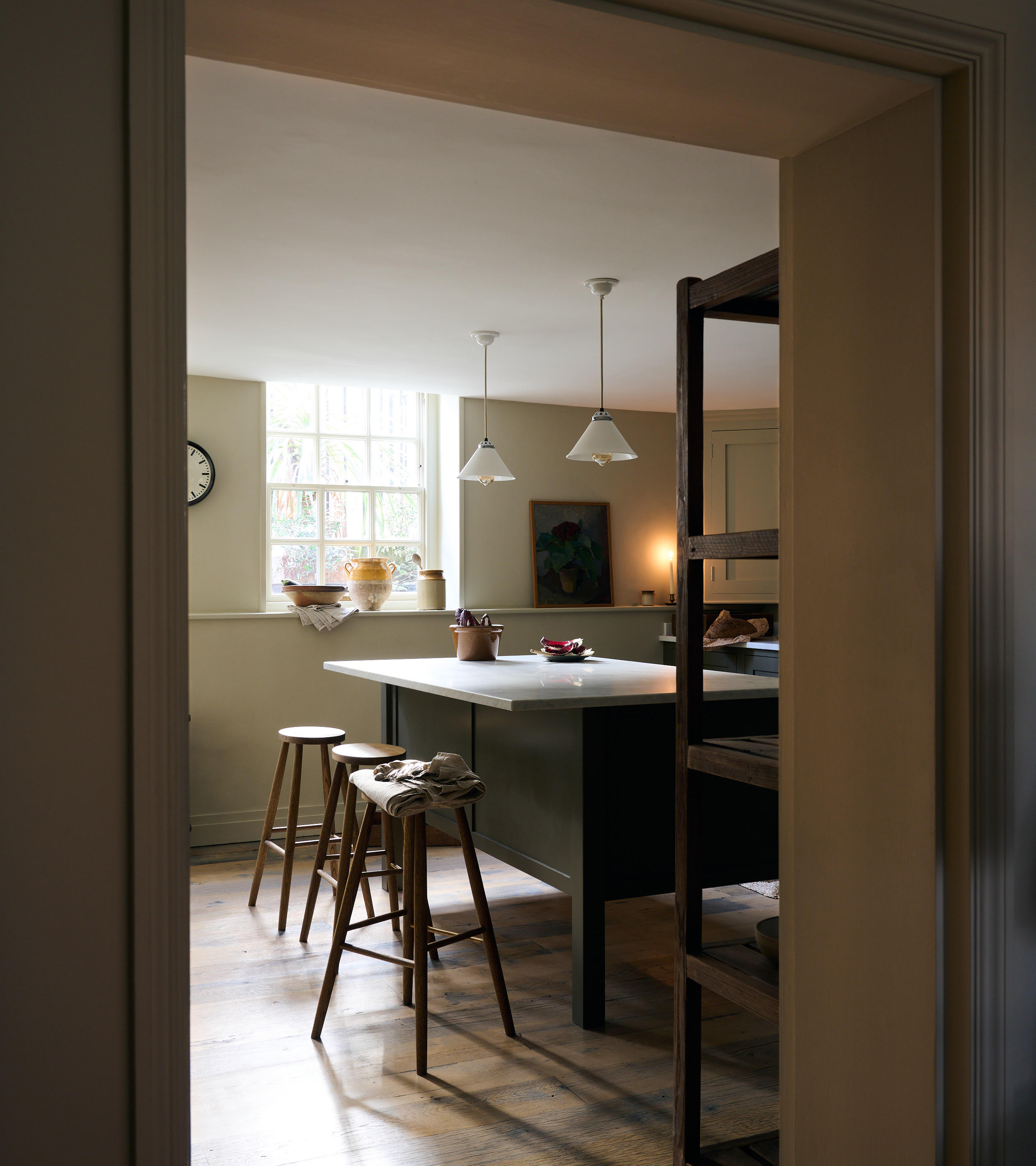 a dark kitchen with a kitchen island, two wooden benches next to it and white kitchen pendant above