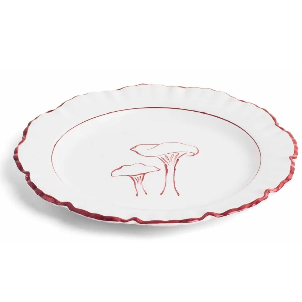 a white plate with ruffled edges with a red mushroom illustration