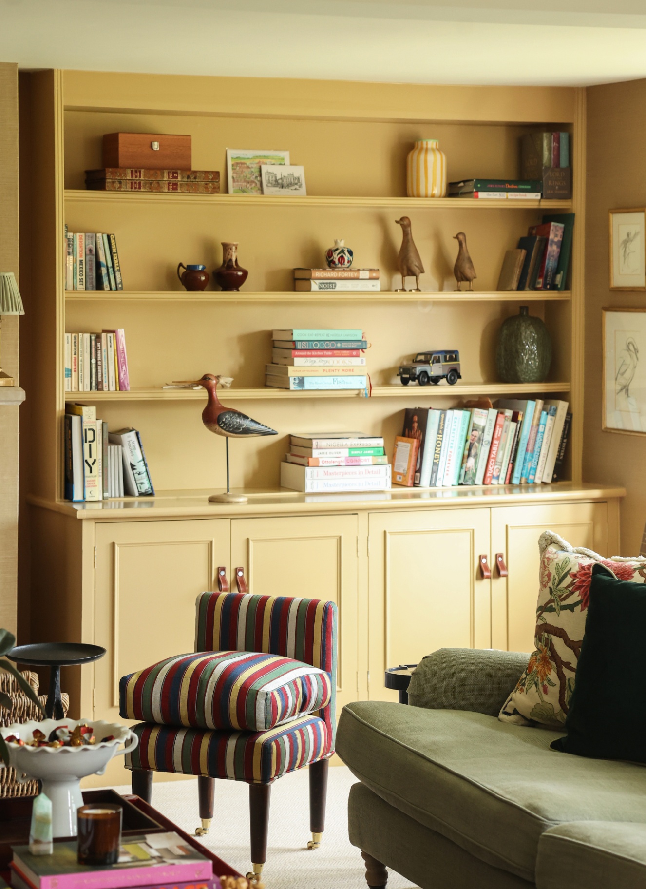 a living room corner wtih a yellow built in alcove and shelving unit