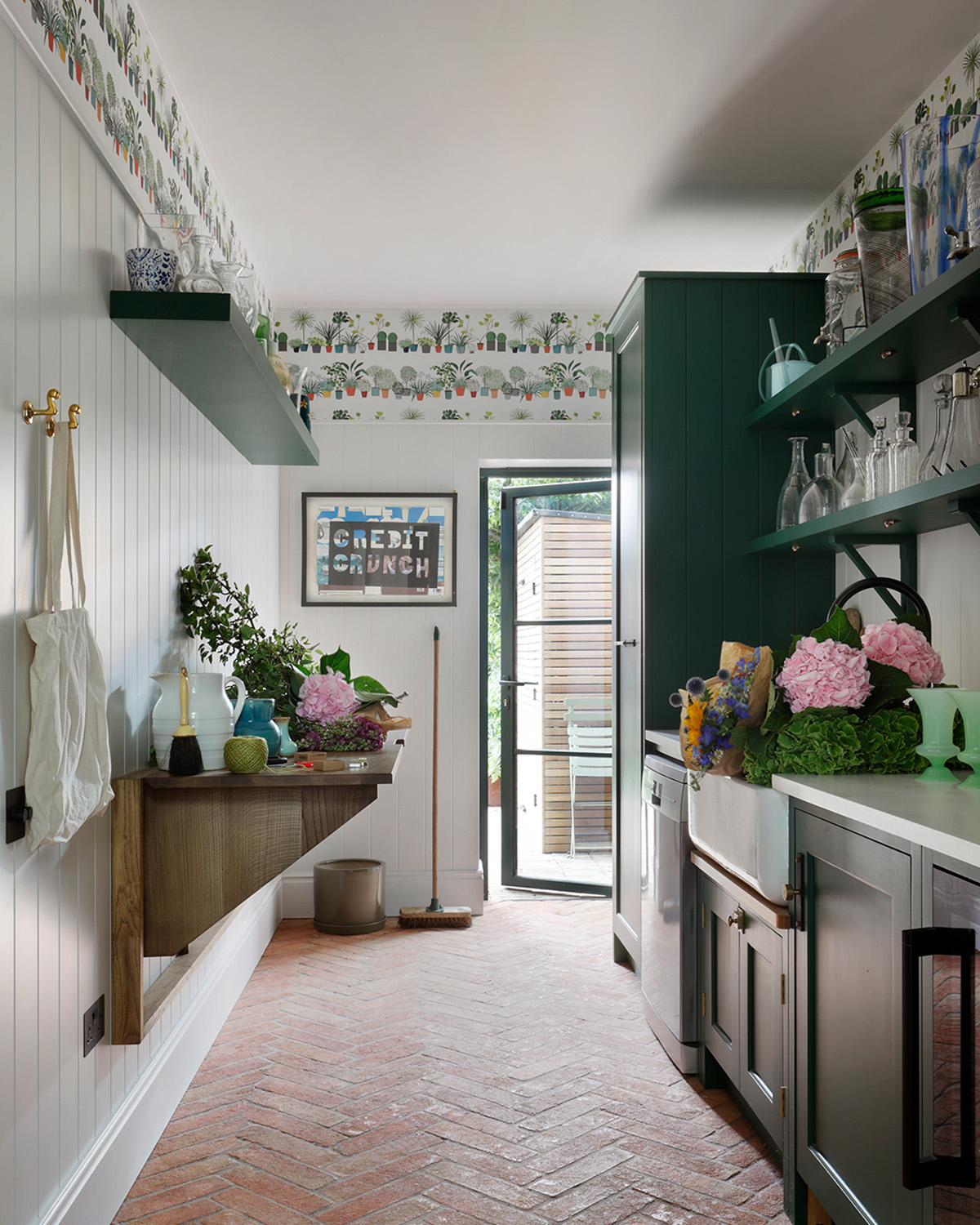 a utility room with brick floors, white paneled walls with a strip of cactus printed wallpaper near the ceiling