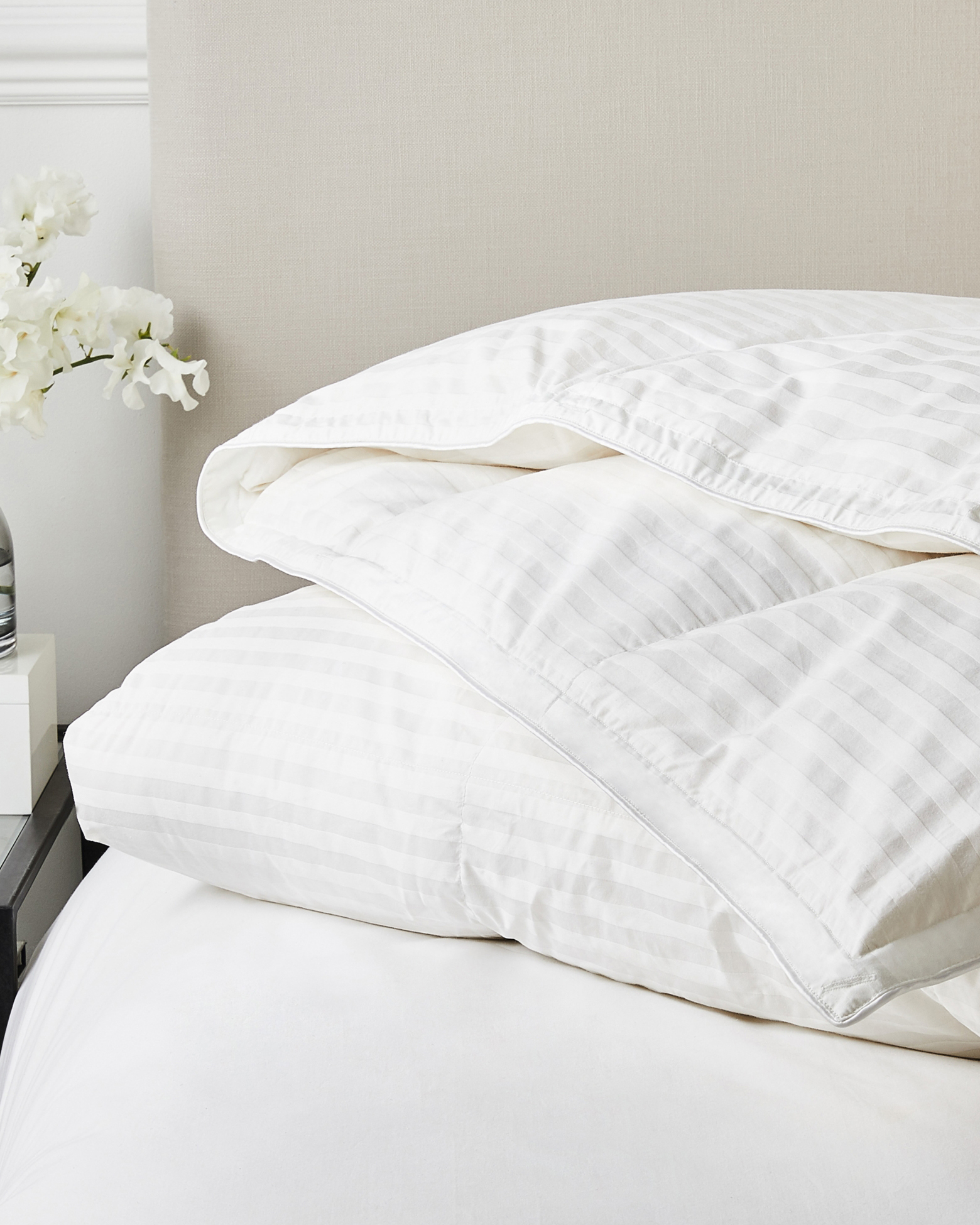 a striped duvet with no cover against a beige headboard