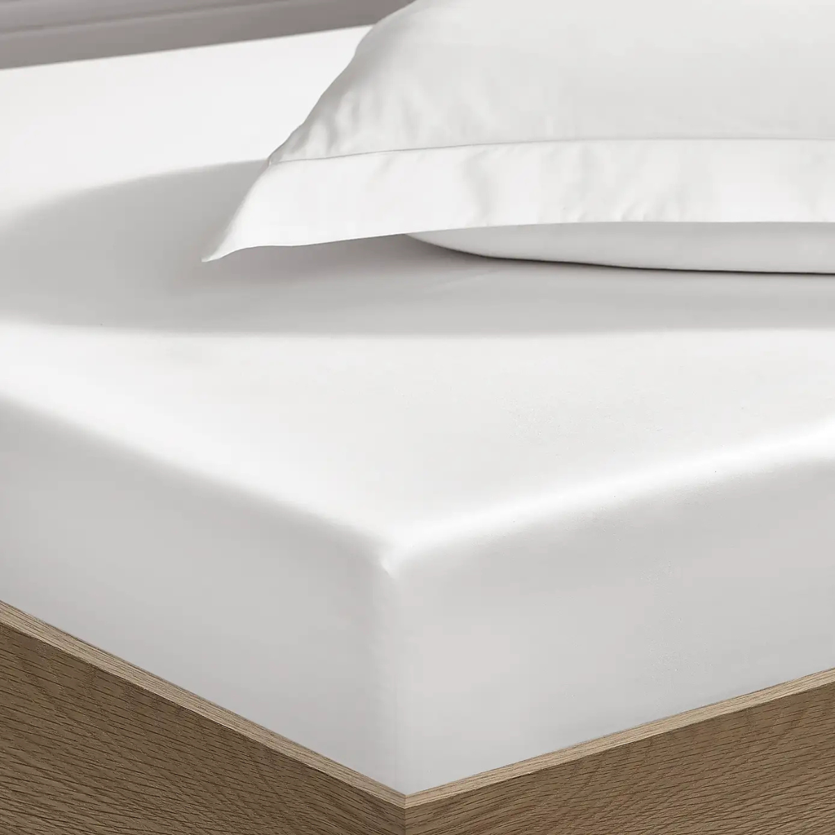 a white fitted sheet on a wooden bed