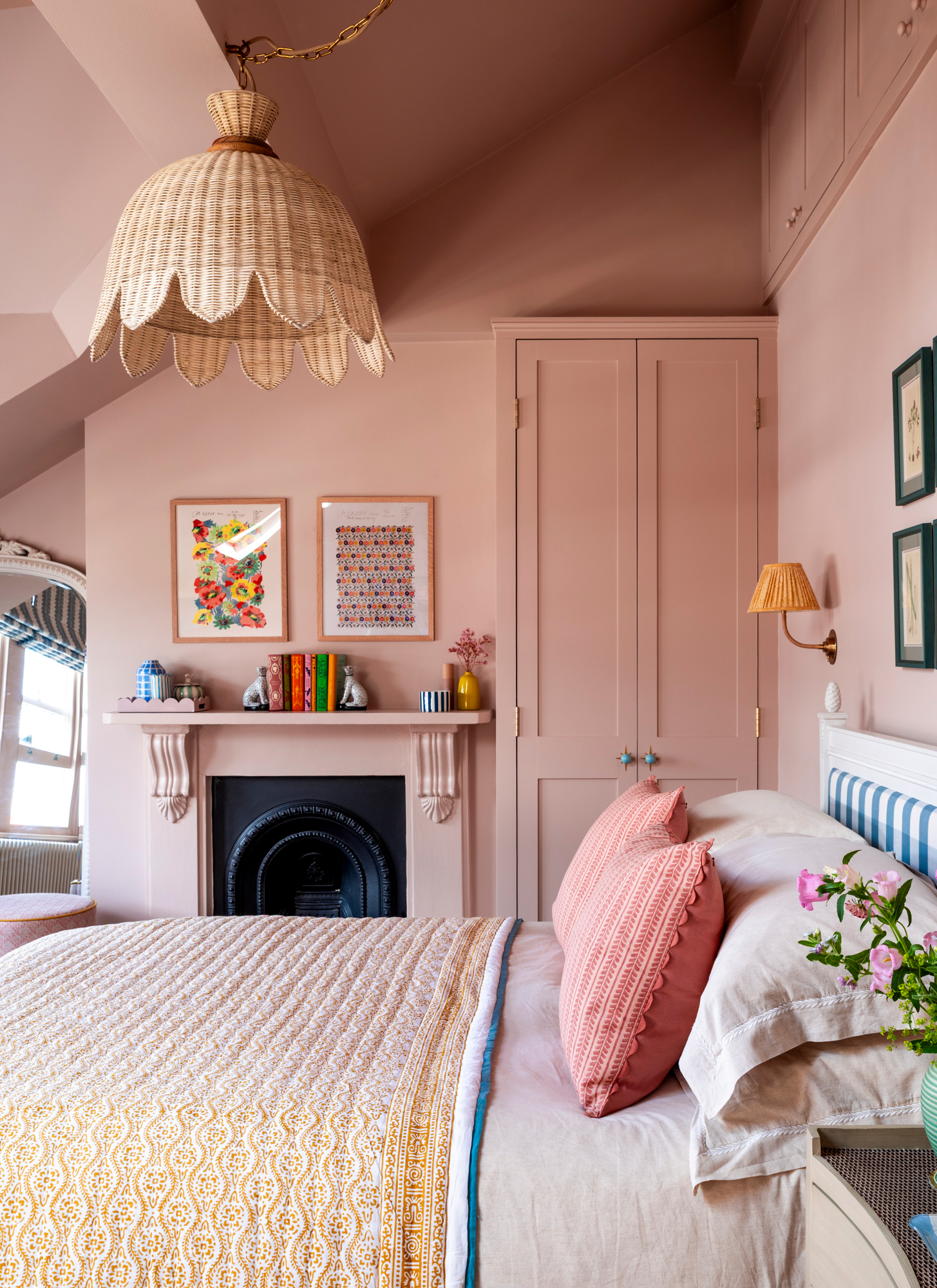 a pale pink colour drenched bedroom with a large rattan pendant light