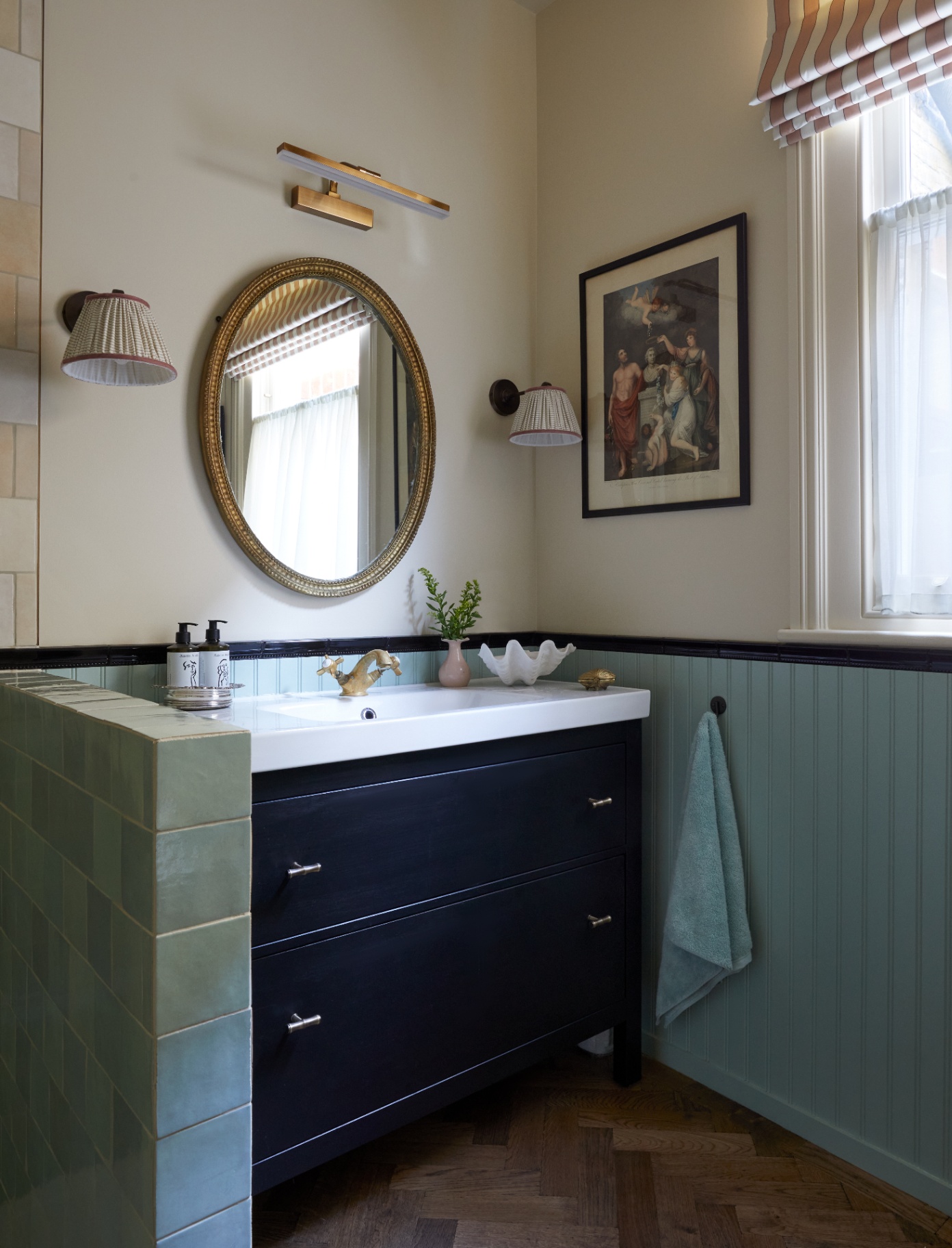 a small corner of a bathroom pictured with the vintage looking sink mirror surrounded by light fixtures, two sconces and one spotlight adorn the walls