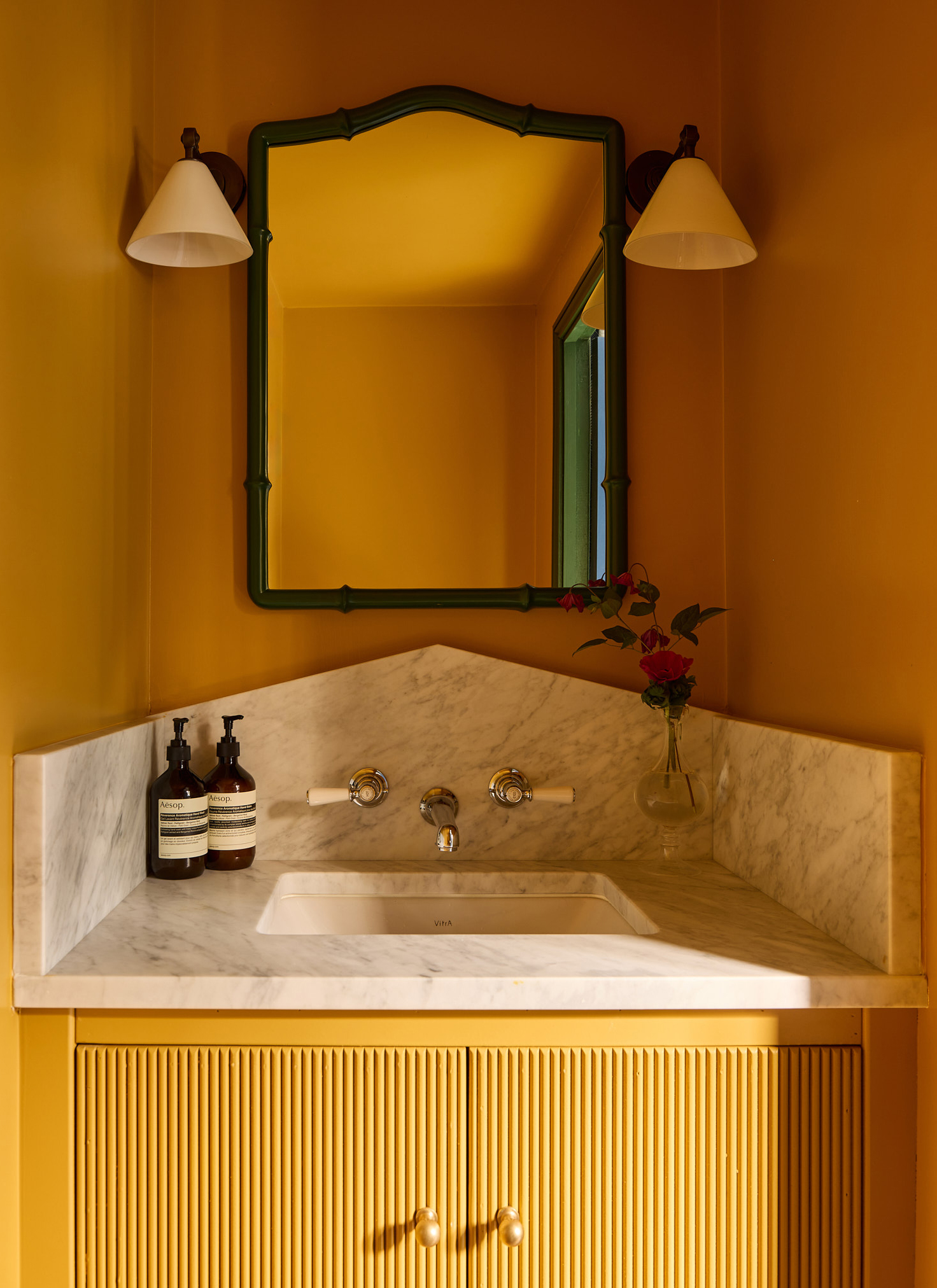 a bright yellow colour drenched downstairs loo with white marble vanity top
