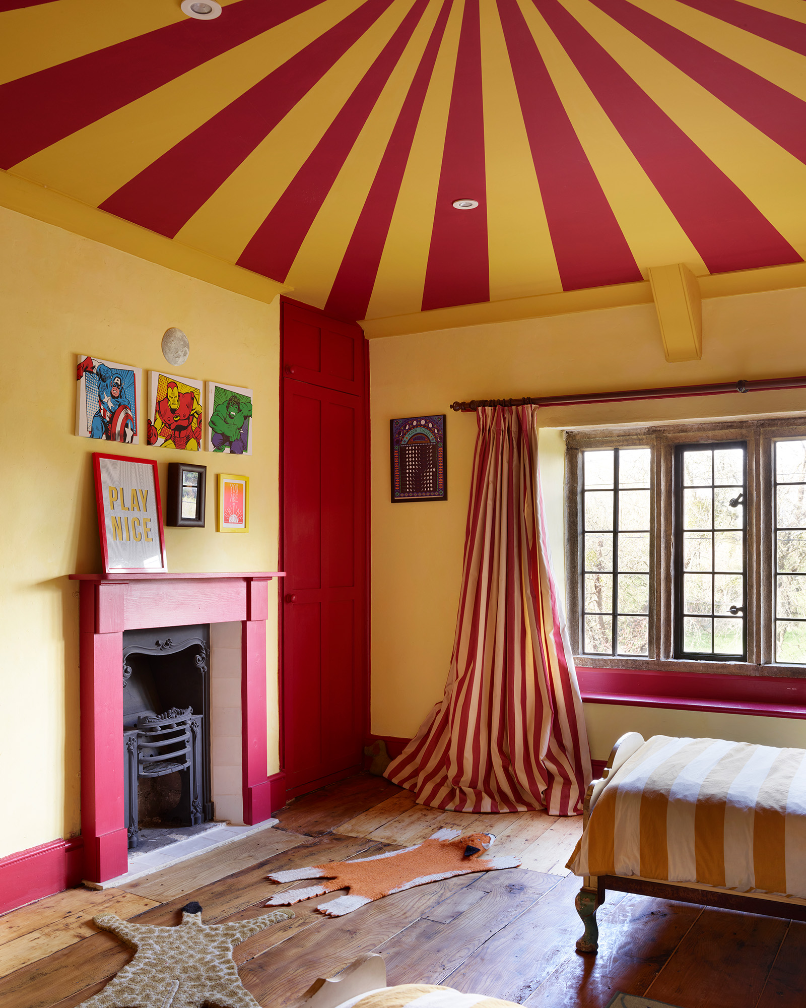 a childrens bedroom with a bold red and yellow circus tent painted ceiling