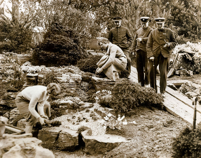 A black and white photograph of three Chelsea Pensioners at the Chelsea Flower Show in 1935