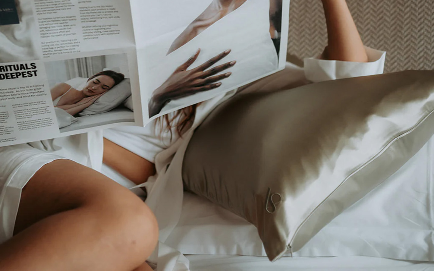 an olive green silk pillowcase and a woman laying on it reading a newspaper