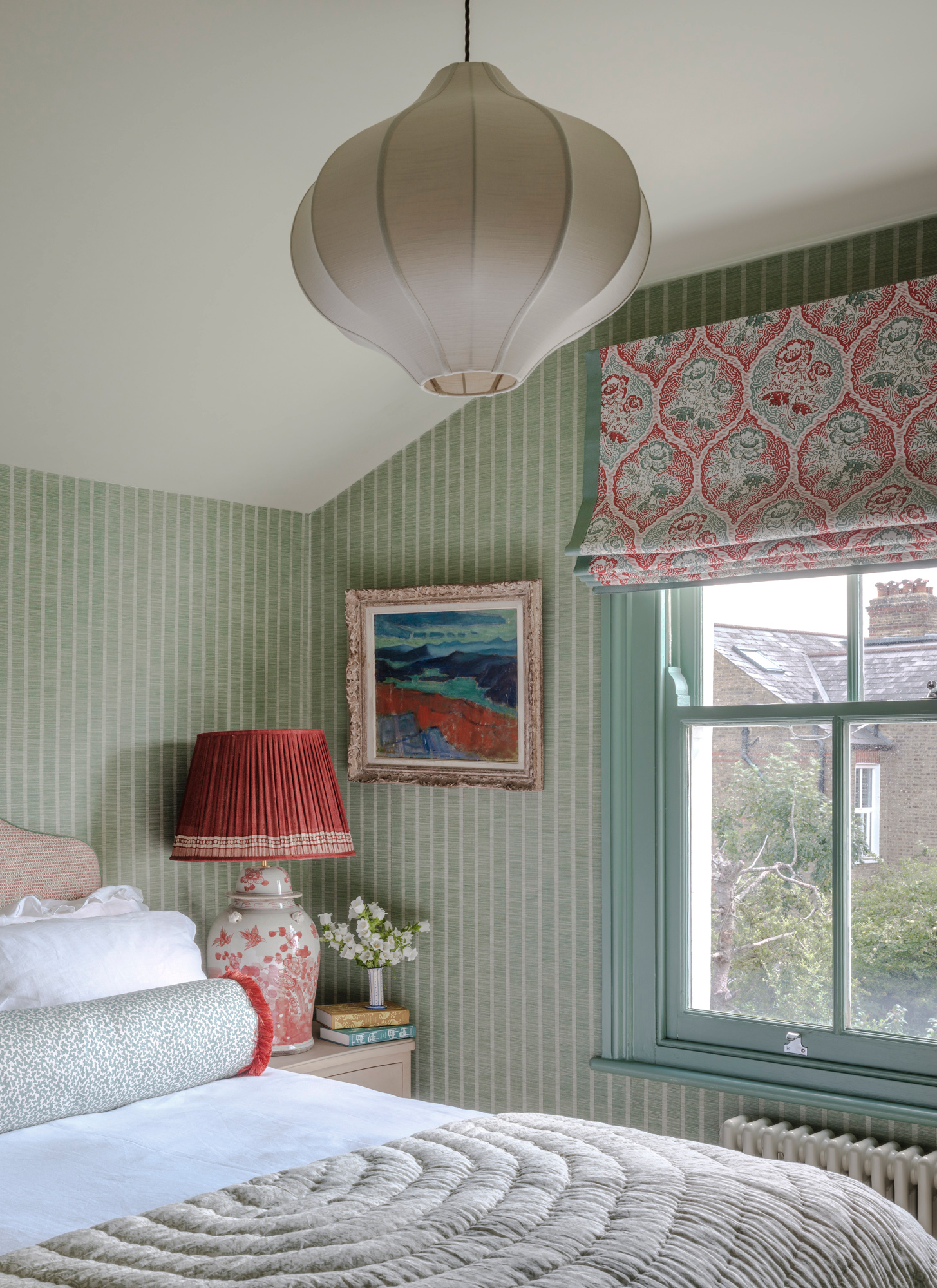 a bedroom with green and white stripe wallpaper and a window with red and green floral fabric pattern