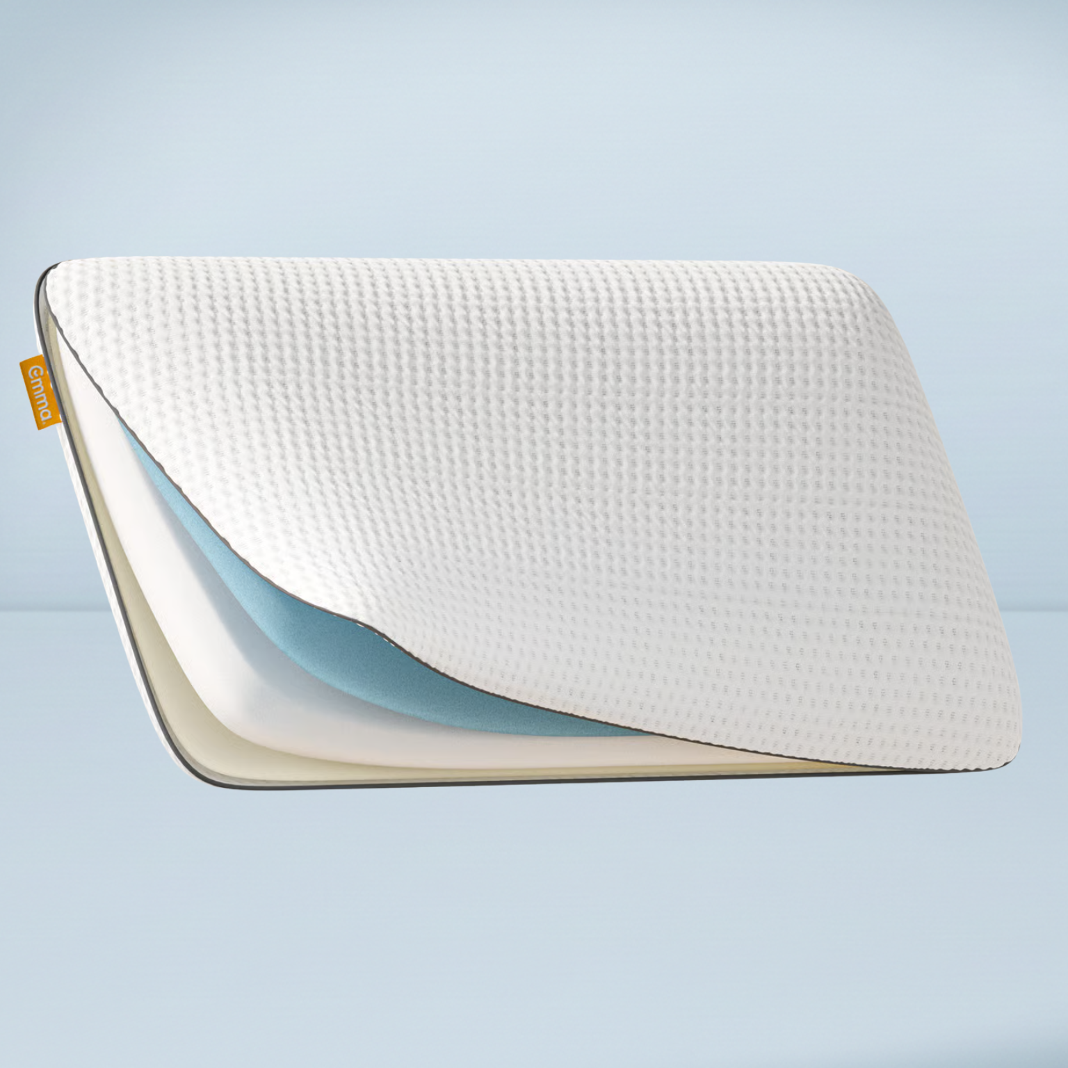 emma hybrid pillow opened up in one corner to reveal the foam layers on a blue background