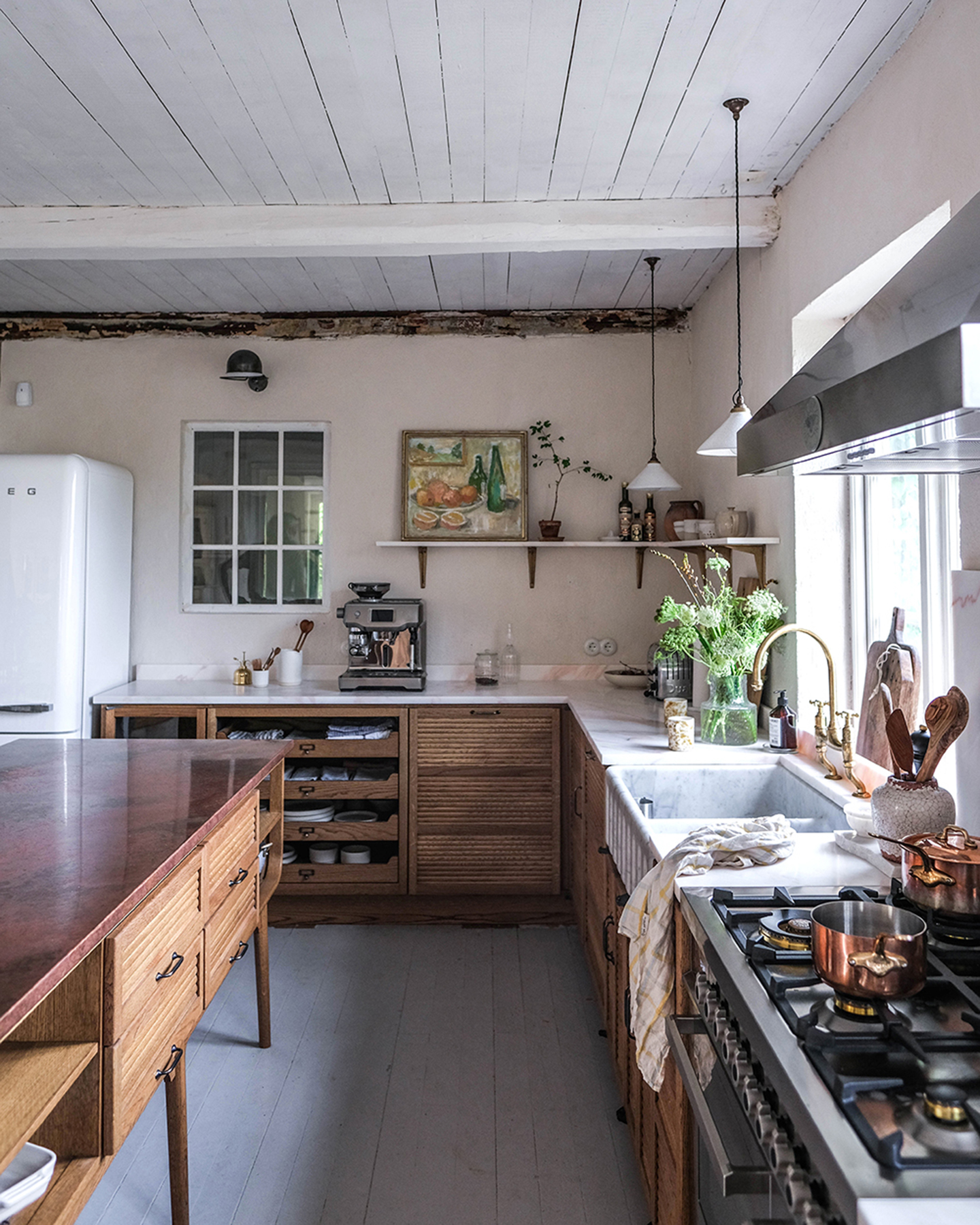 A kitchen with white walls, brown wooden cabinets, a wooden kitchen island and open shelving