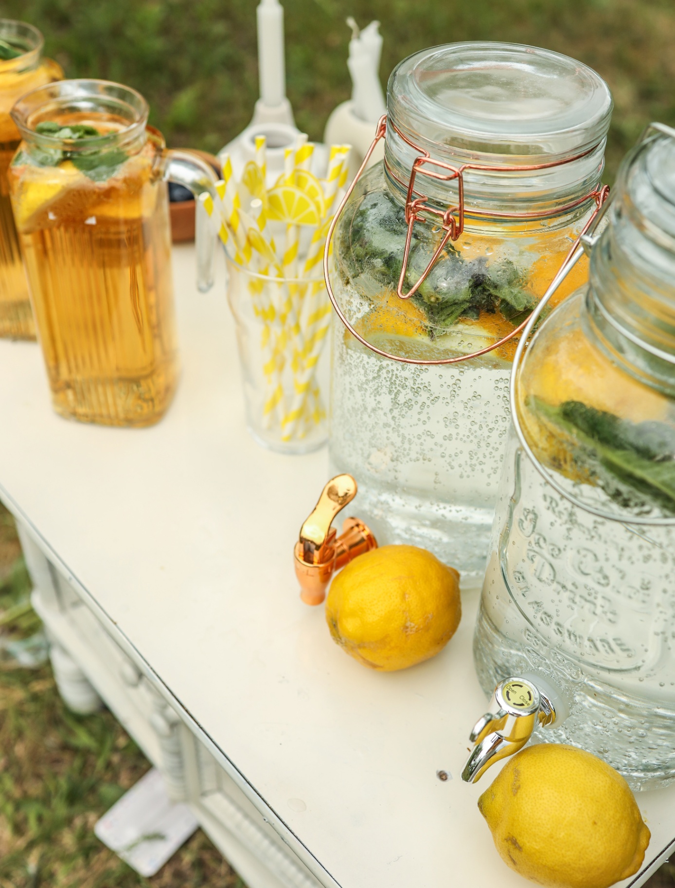an outdoor table with a large glass drink dispenser and lemons