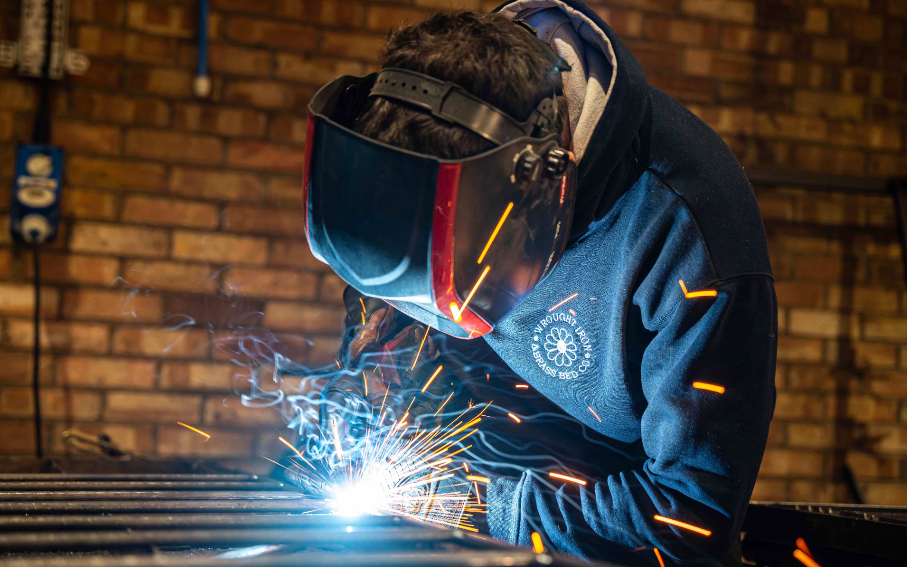 a man with a welder and mask making an iron bed
