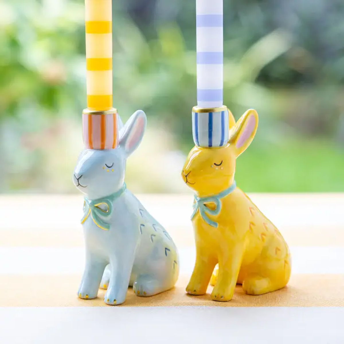 a yellow and a blue candle stick holder in shape of bunny