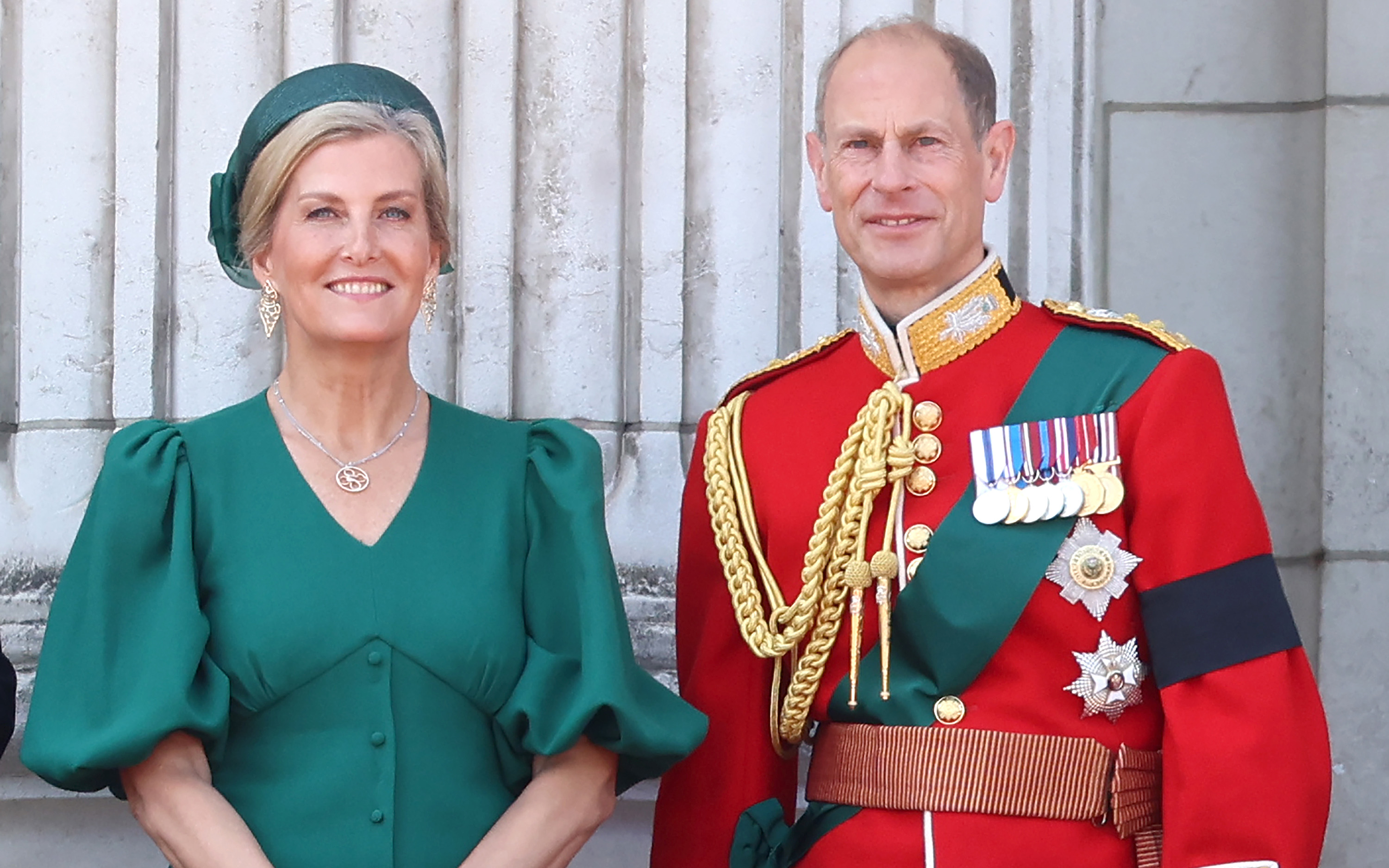 the duke and duchess of edinburgh, edward wearing red ceremonial outfit and sophie wearing an emerald green dress