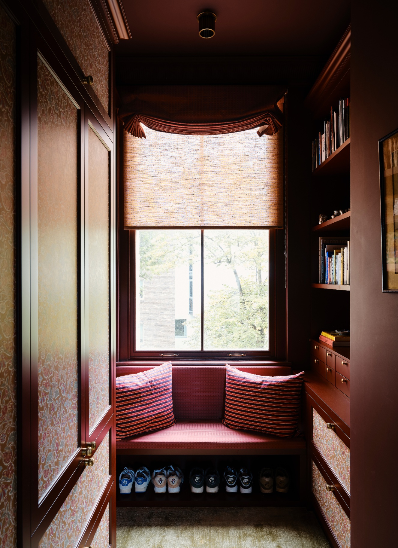 a narrow dressing room with a window seat colour drenched in dark red