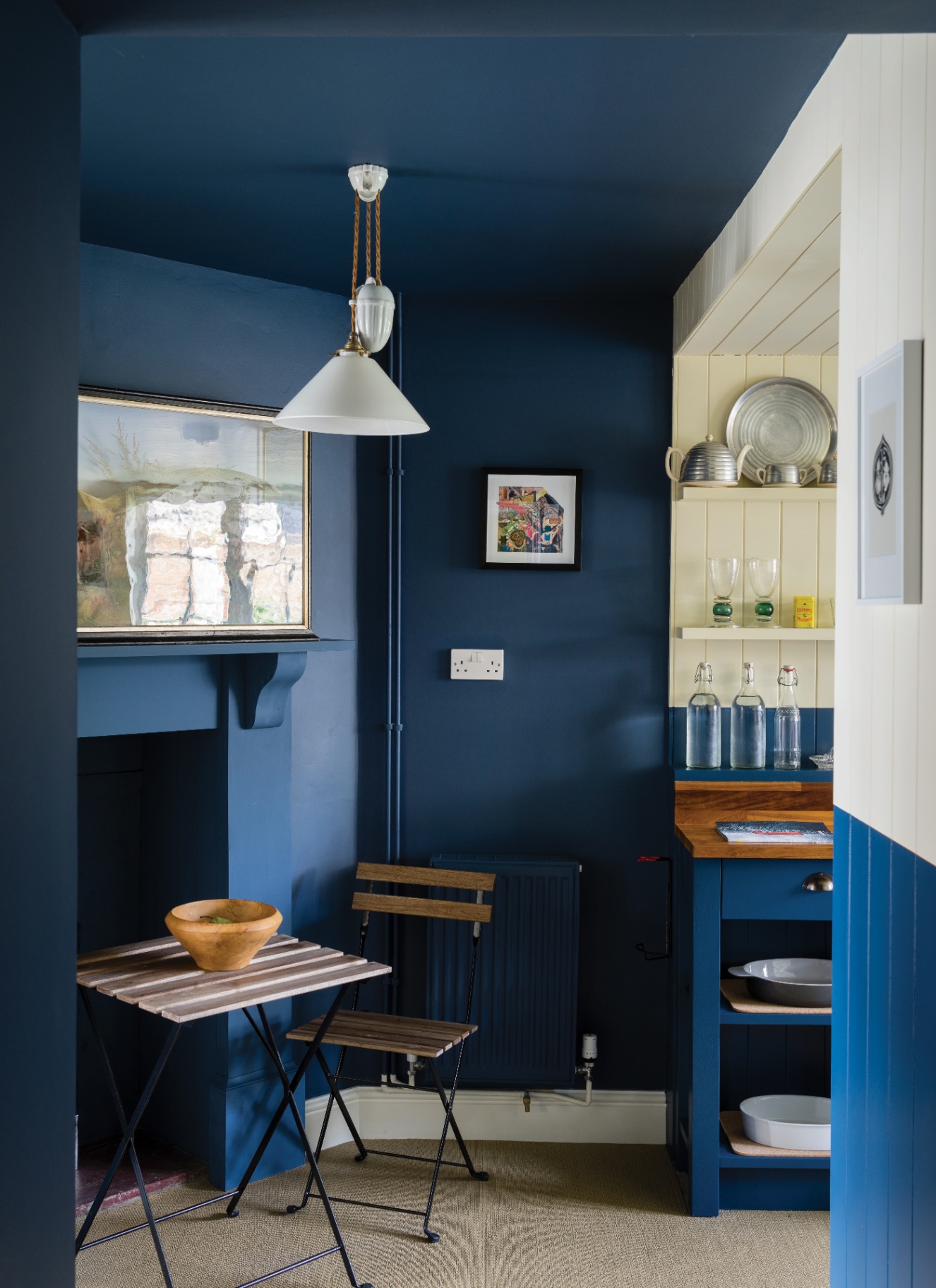 a dining area with navy blue drenched walls and ceiling, a fireplace and a small wooden bistro table and chairs