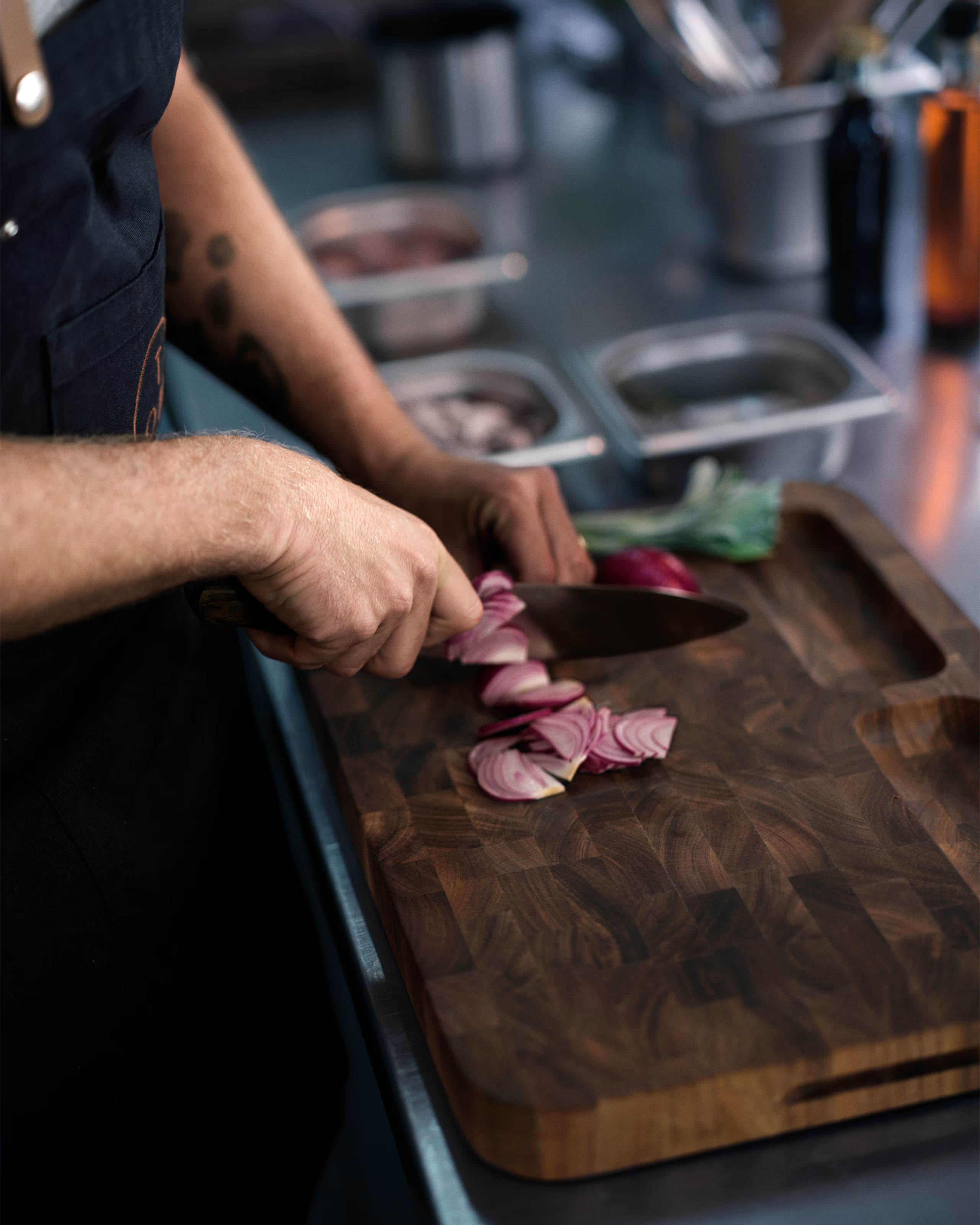 tom kerridge chopping board with someone cutting a red onion on it