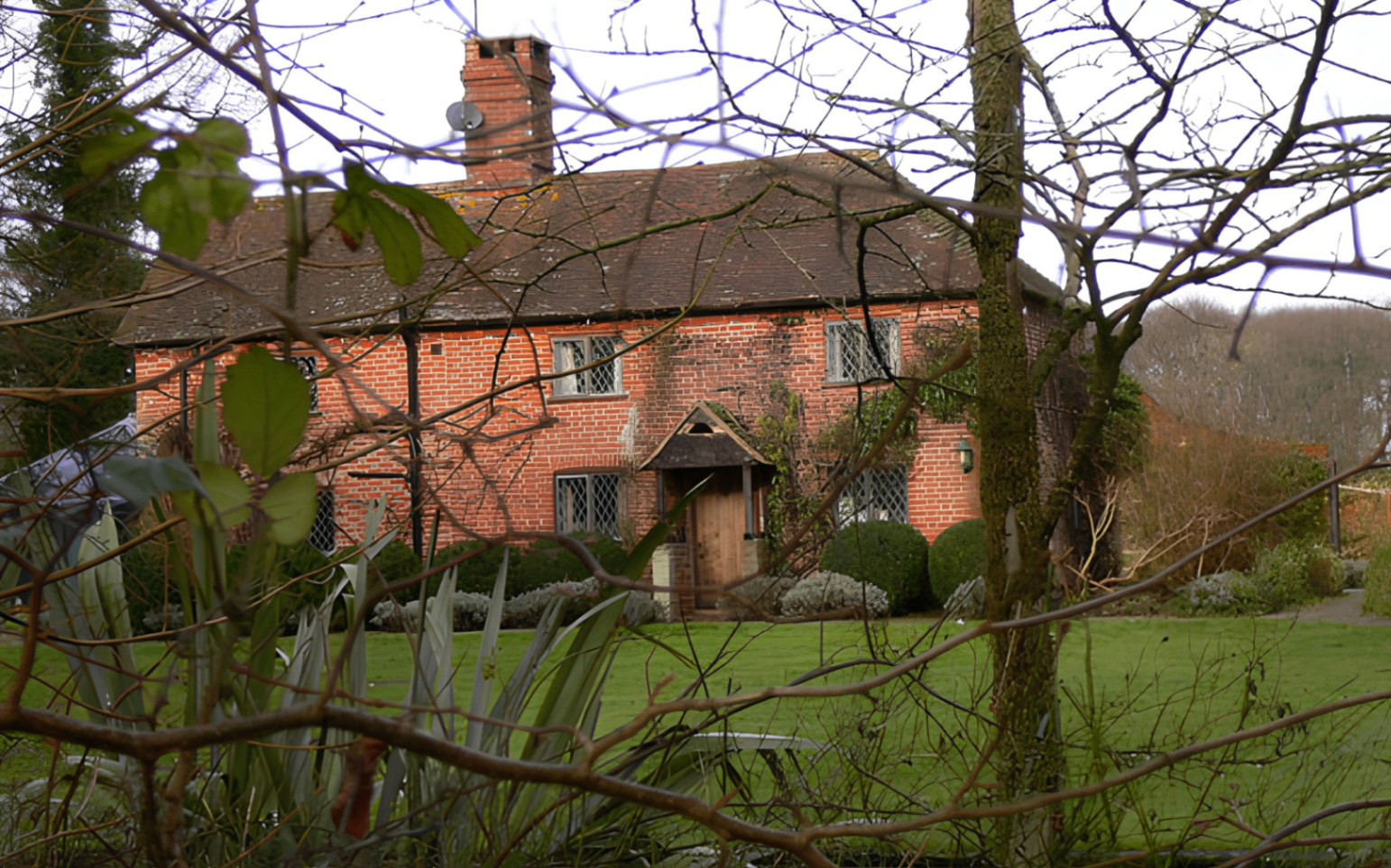 lee wood farm, a red brick farmhouse with trees in the foreground, julie walters home in sussex