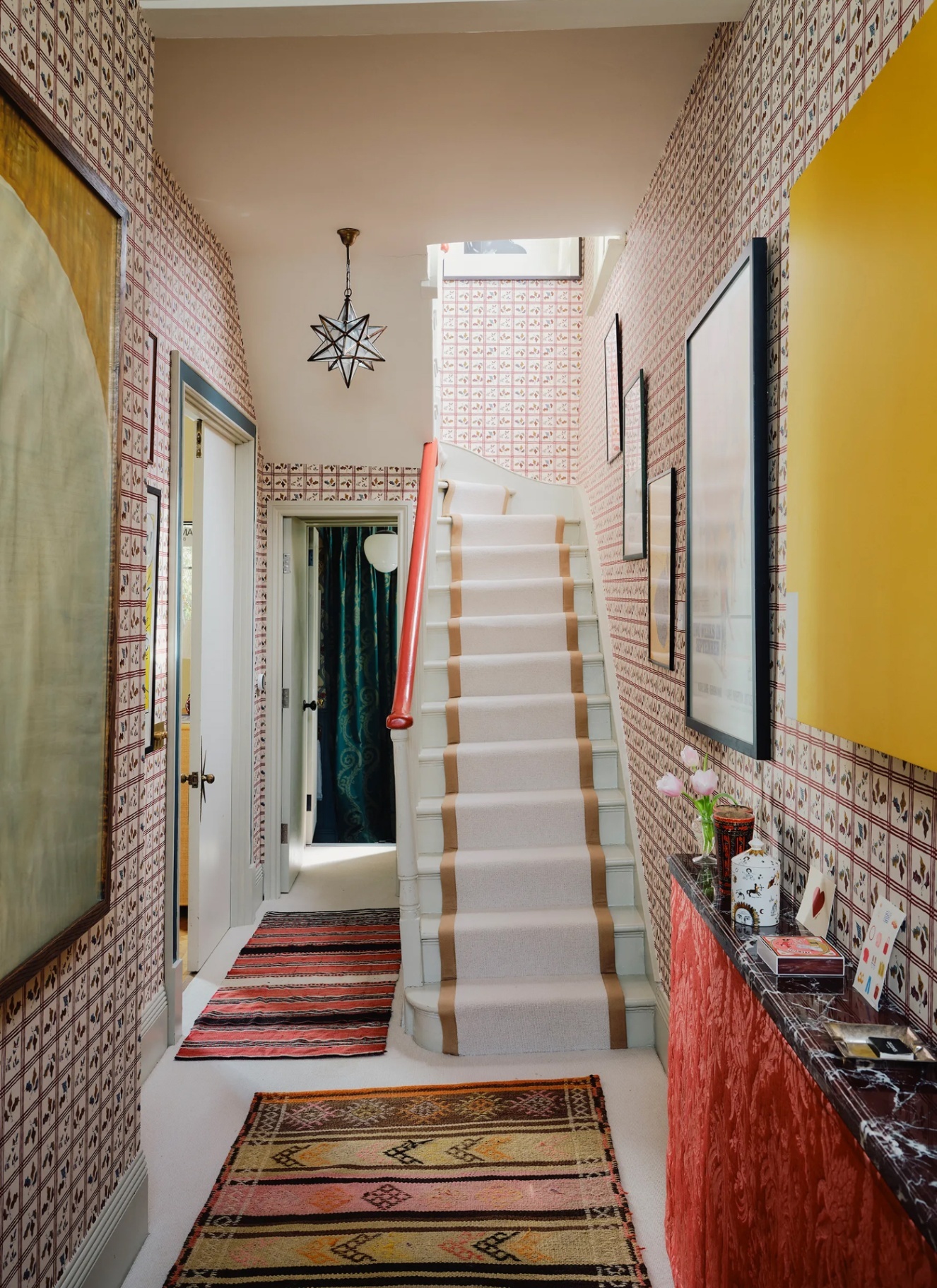 a hallway with a star pendant light, white and dark red patterned wallpaper and star with cream runner
