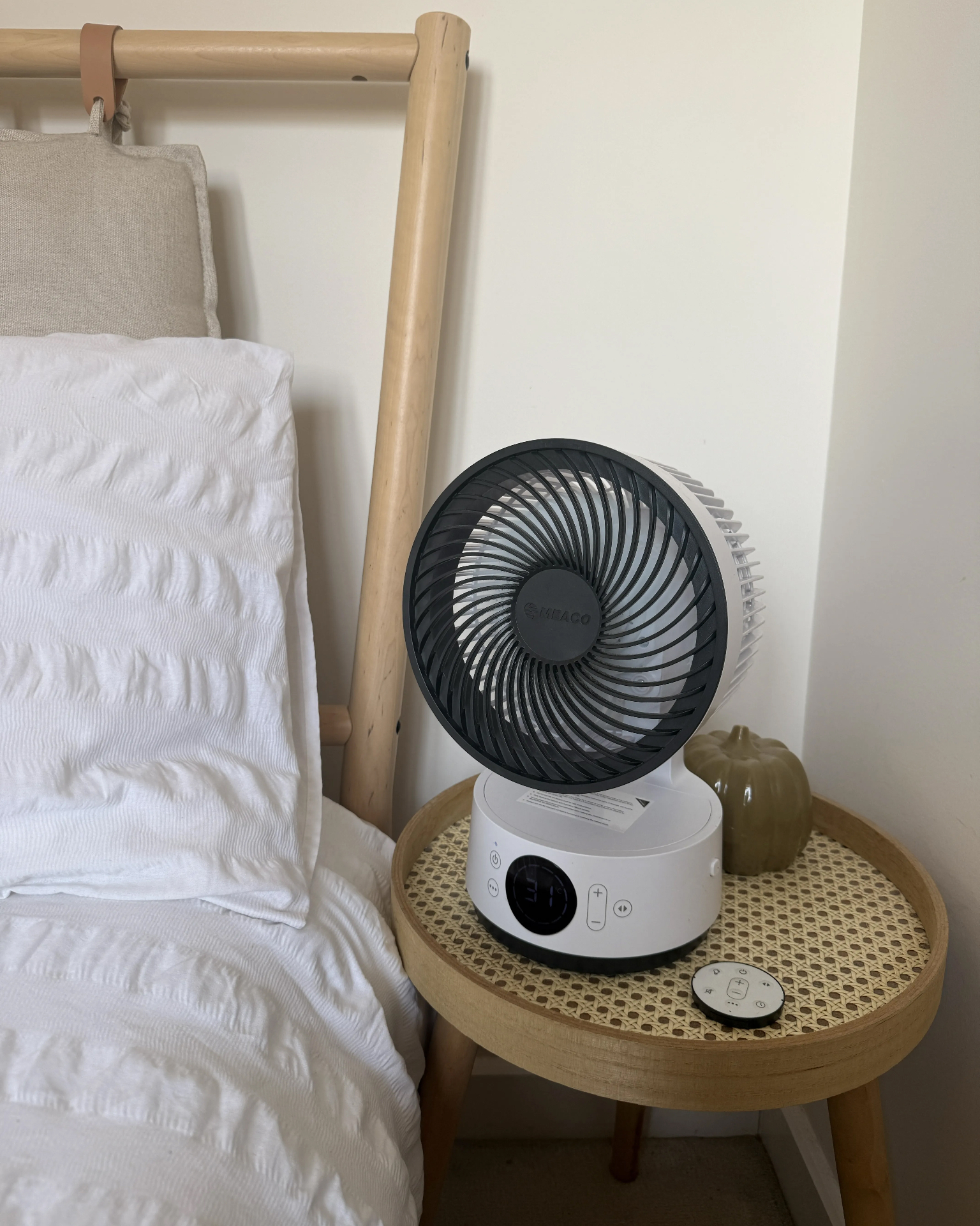meaco desk fan on a rattan side table next to a wooden bed with white bedding