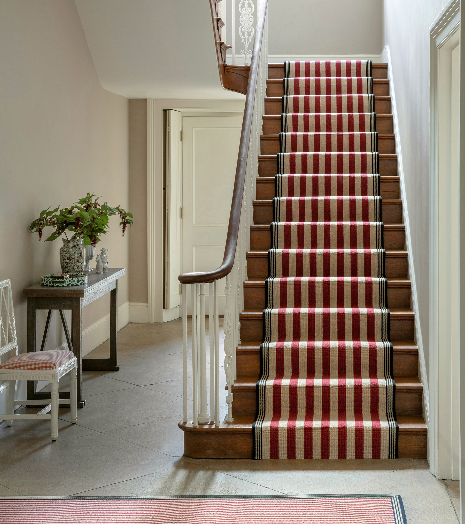 a hallway with a red and white stripe stairs runner