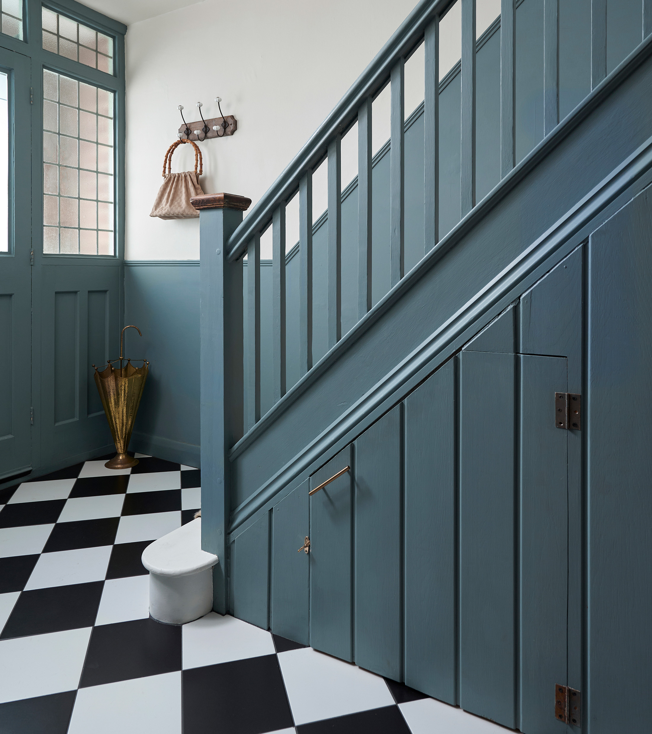 hallway with black and white flooring and blue painted stairs