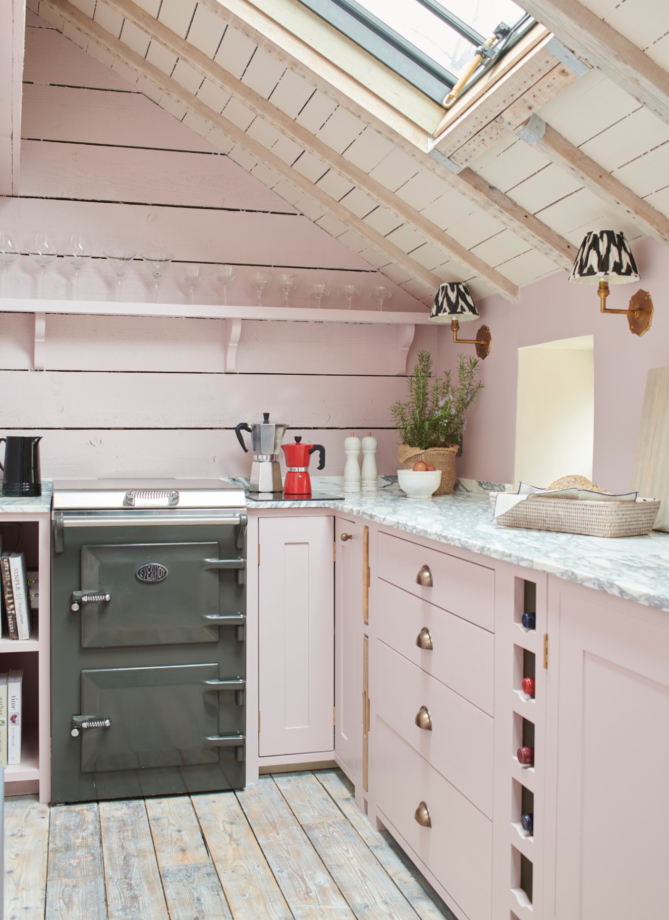 a small kitchen with pale pink panelled walls, pale pink cabinetry and a slim dark grey everhot cooker