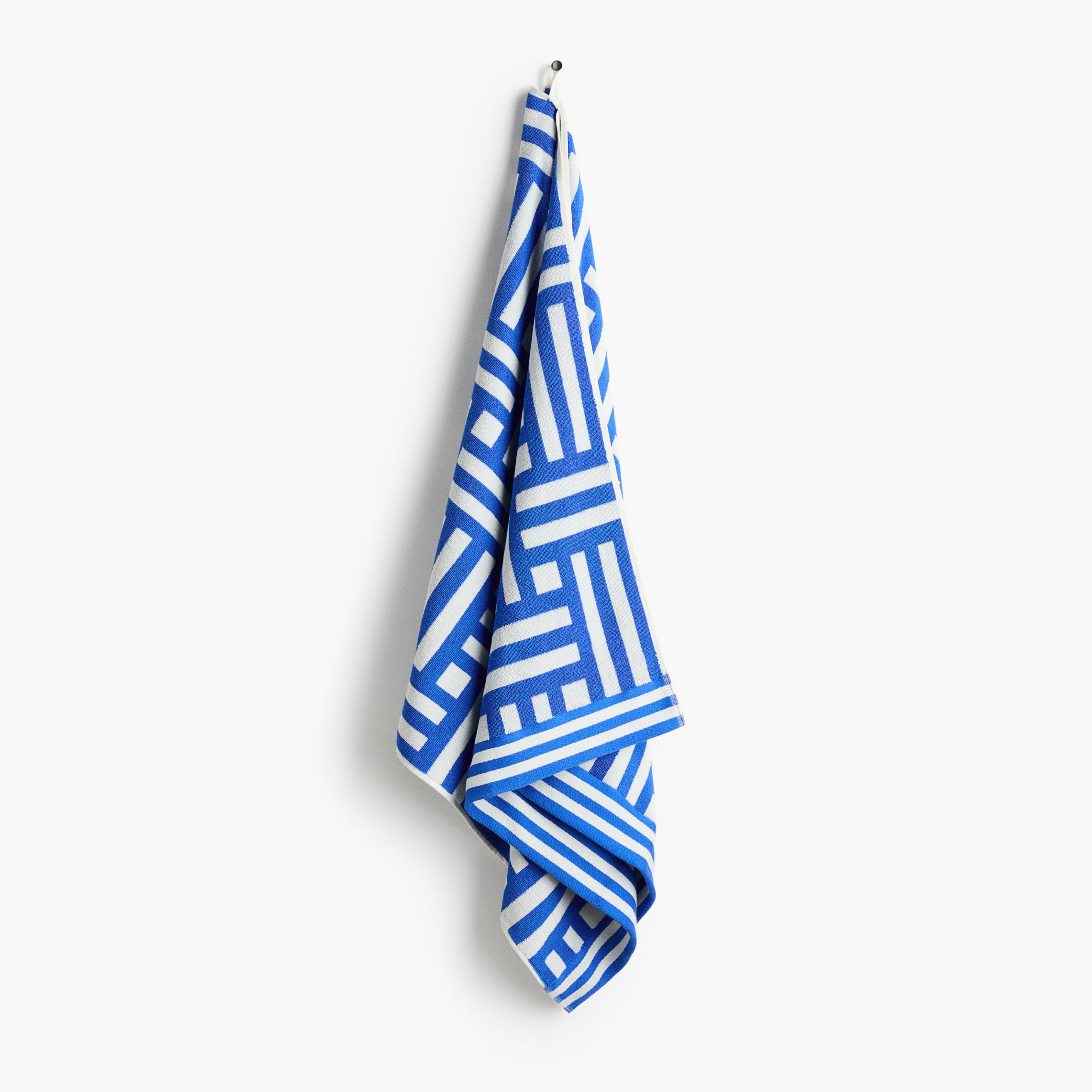 h&m Patterned Cotton Beach Towel blue design pictured geometric pattern hung on a hook on a white background
