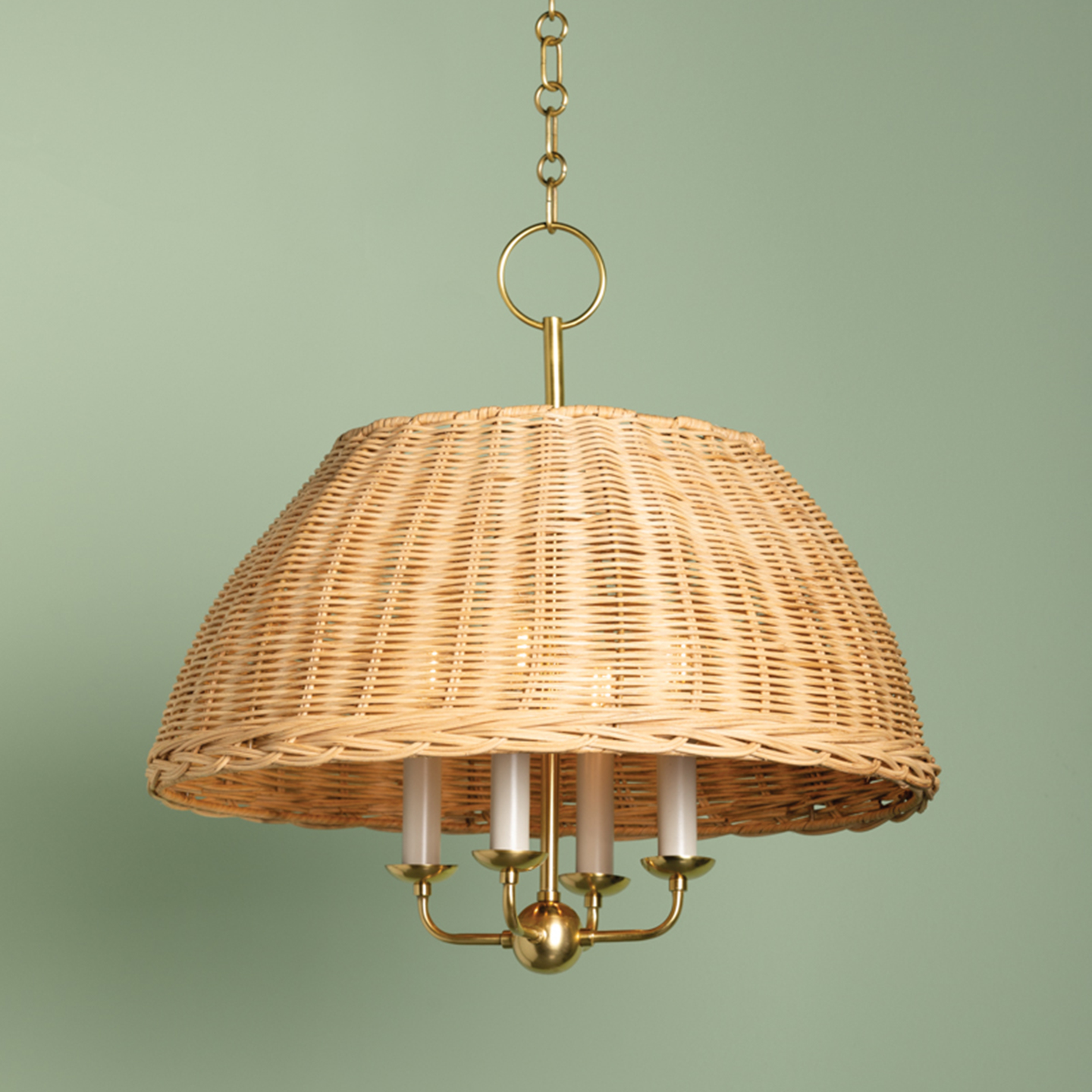 a light brown rattan chandellier light with gold hardware on a soft green background